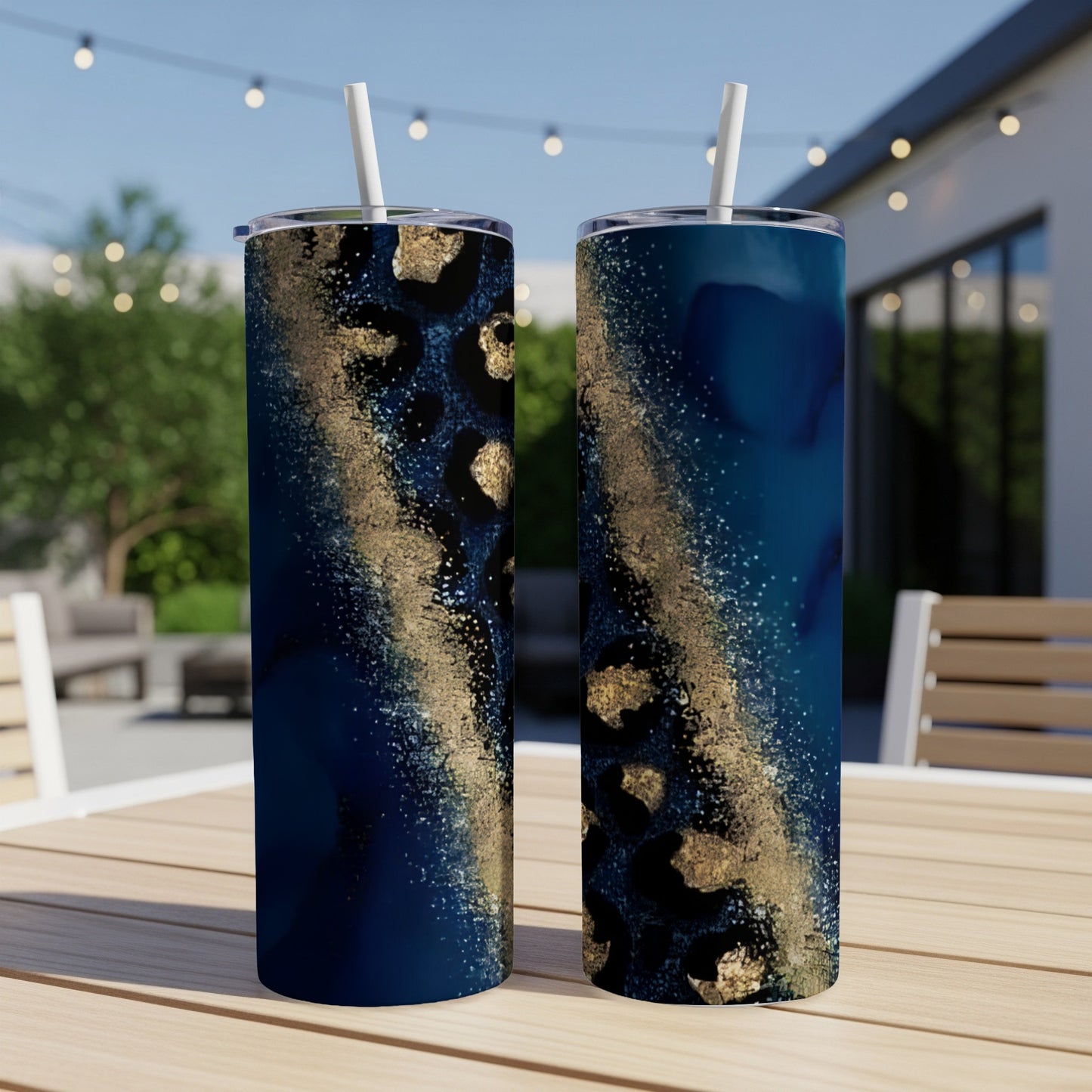 Two tall tumblers with dark blue and gold leopard print design on a table.