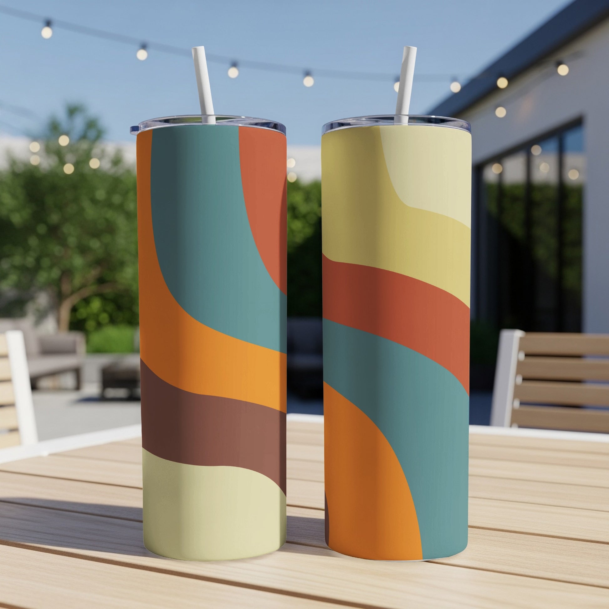 Two tumblers with abstract wavy patterns in muted colors on a wooden table.