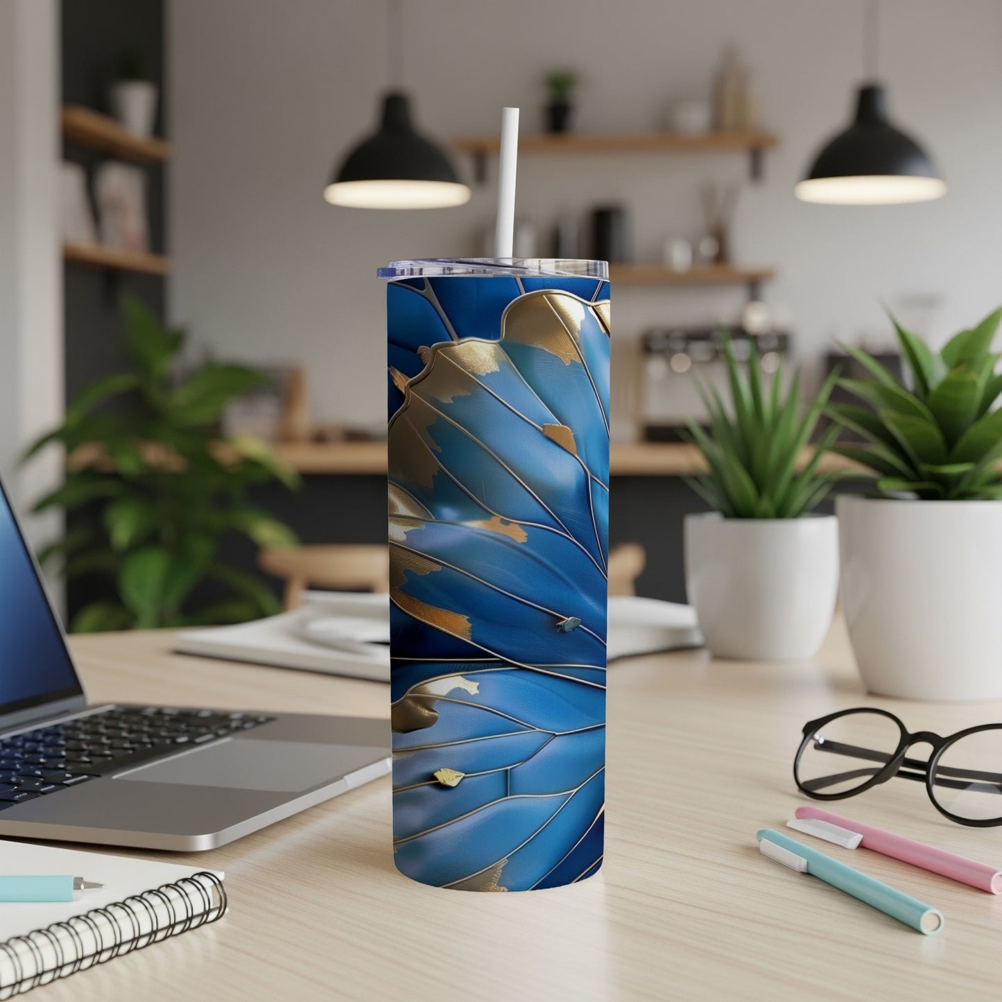 Blue and gold patterned tumbler with straw on a desk.