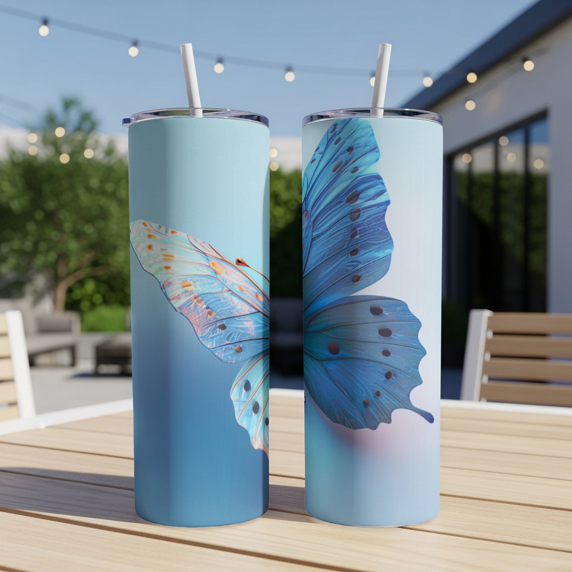 Two blue butterfly tumblers with straws on a wooden table.