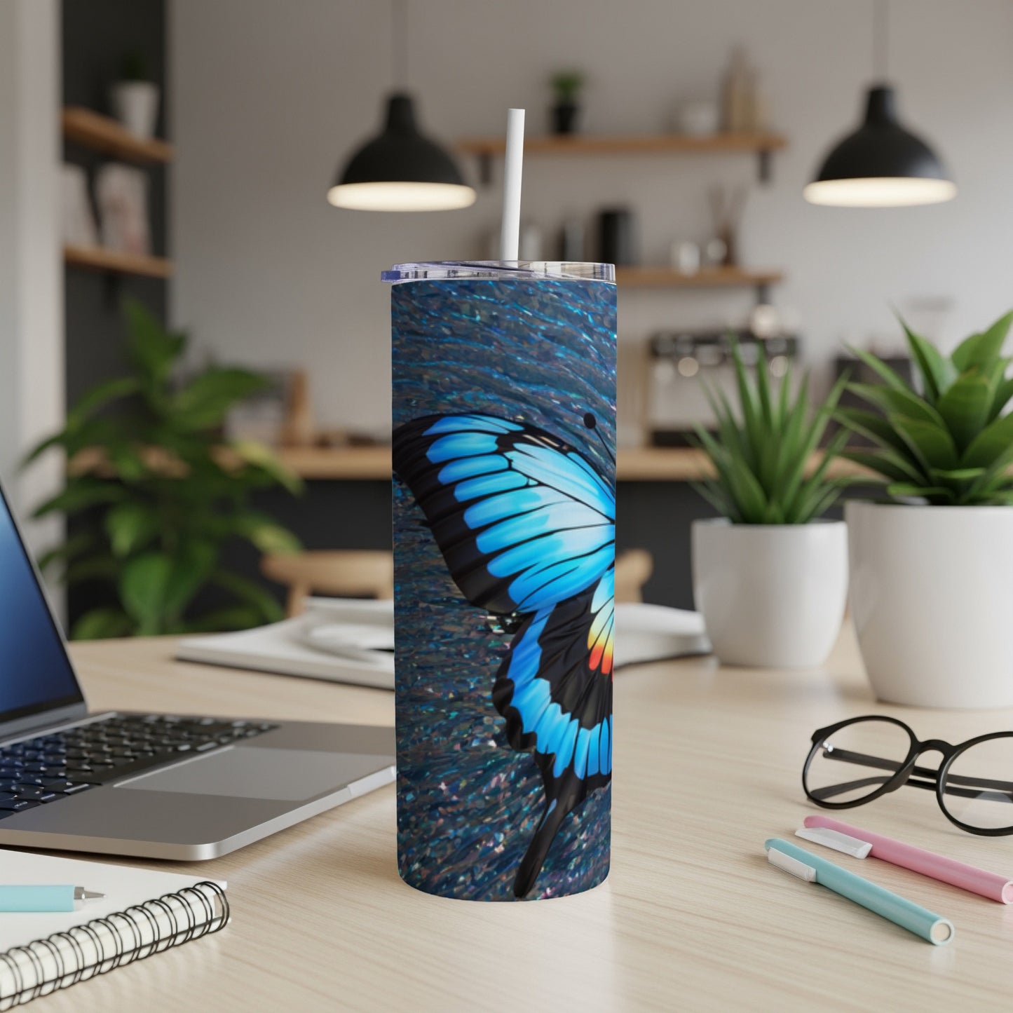 Blue butterfly design on a tall, slender tumbler with a straw.