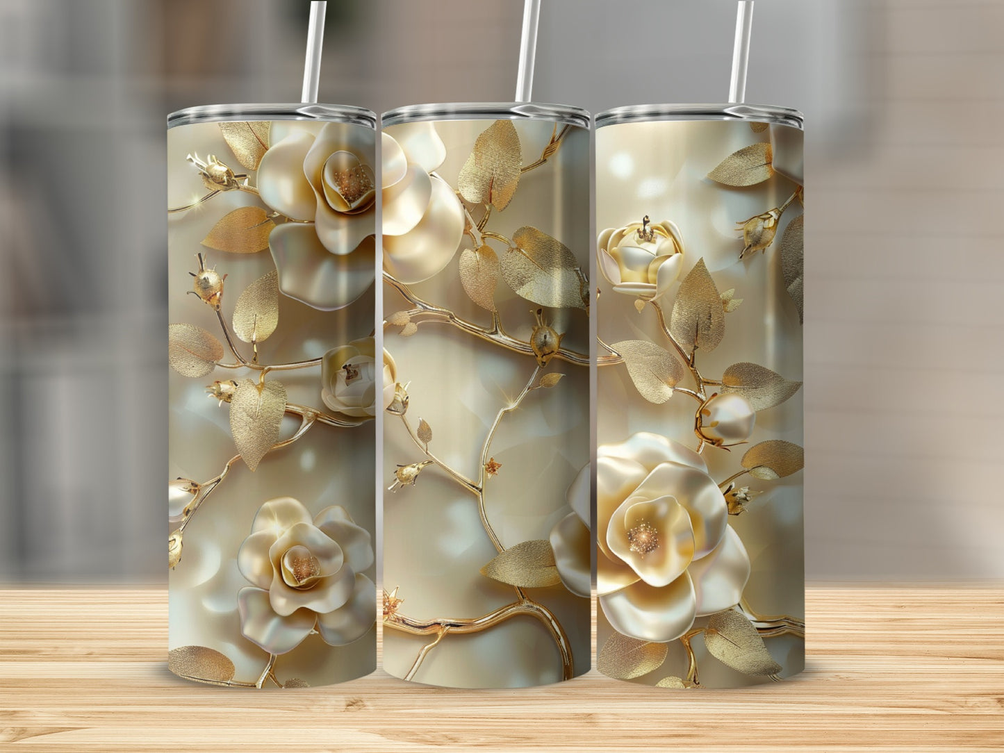 Three gold and cream tumblers with floral embellishments and straws.