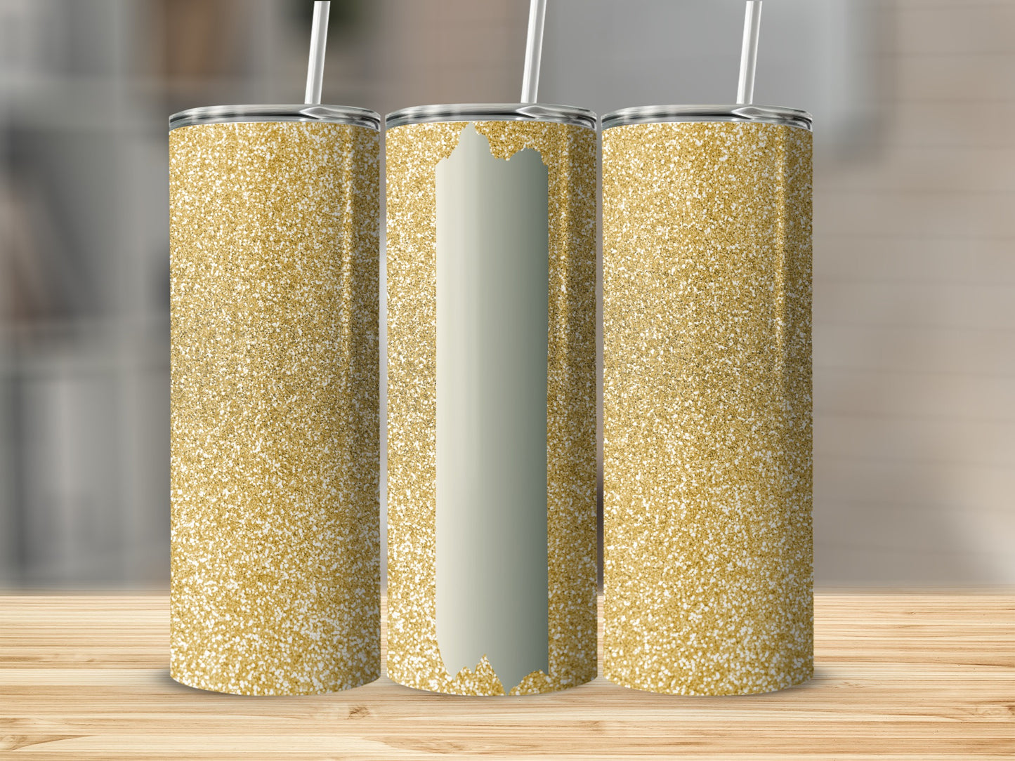 Three glittery gold tumblers with straws on a wooden surface.