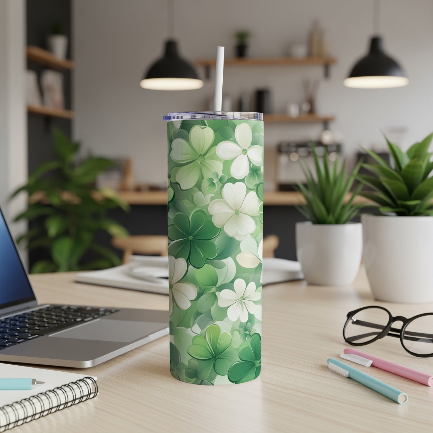 Green clover floral pattern tumbler with a straw on a desk.