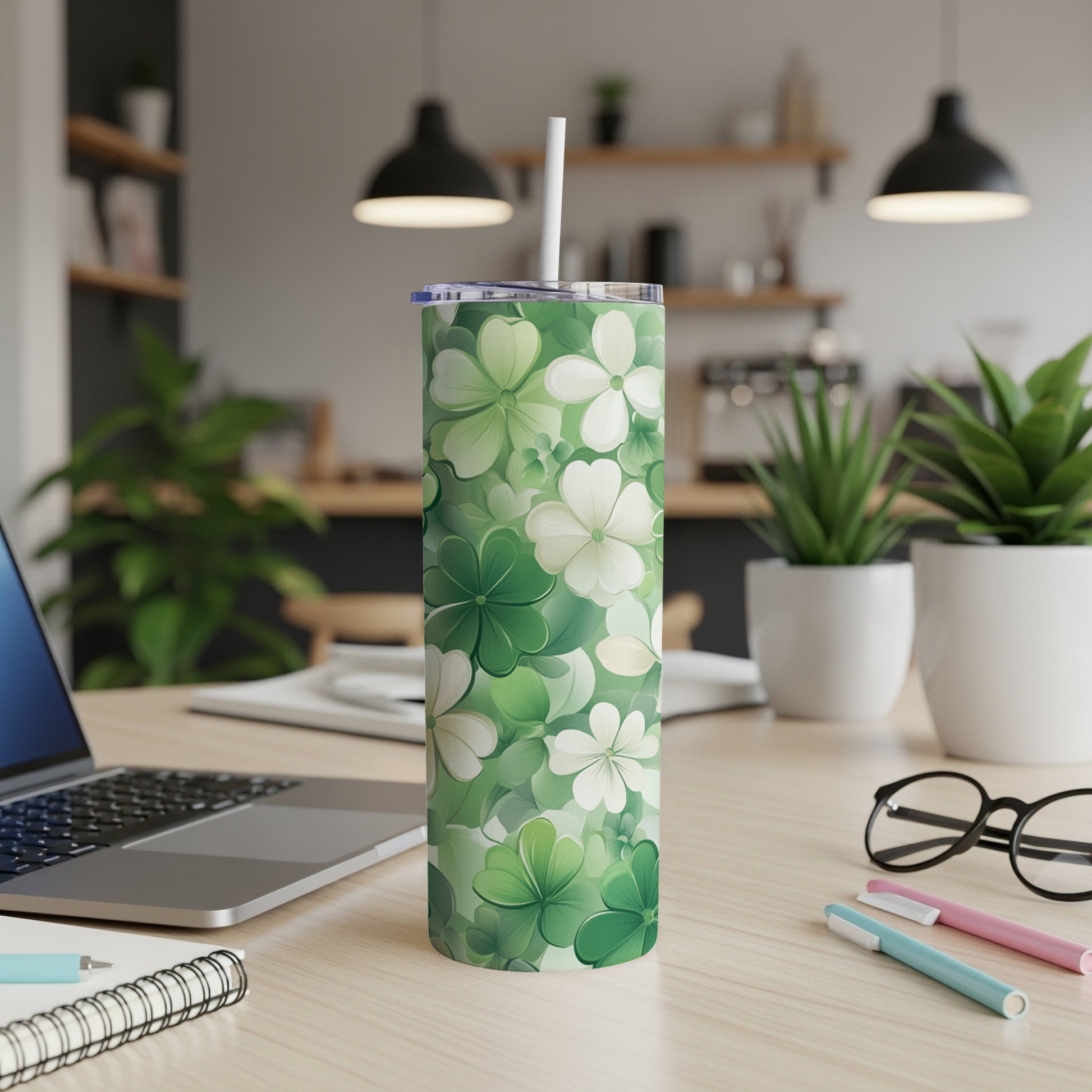 Green clover floral pattern tumbler with a straw on a desk.