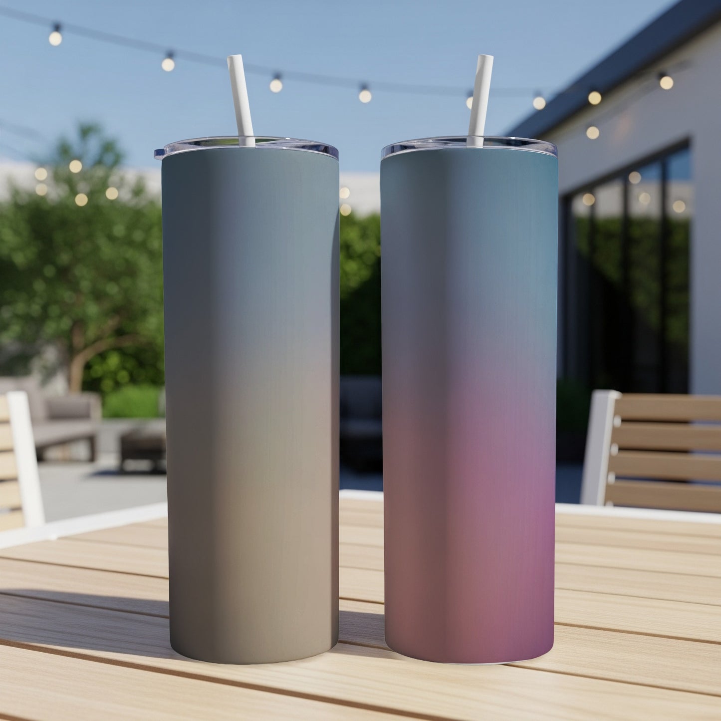 Two gradient tumblers with straws stand on a wooden table outdoors.