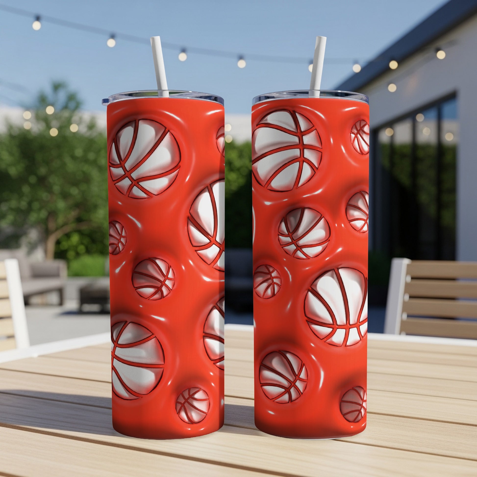 Two red tumblers with basketballs imprinted on a wooden table outdoors.