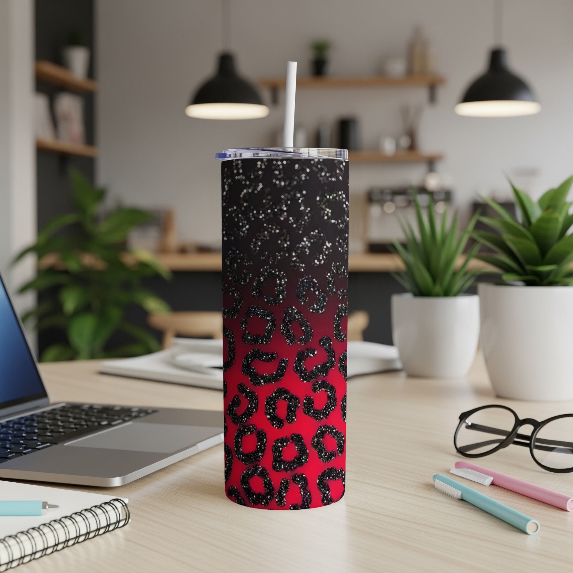 Red and black leopard print tumbler with straw on a desk.