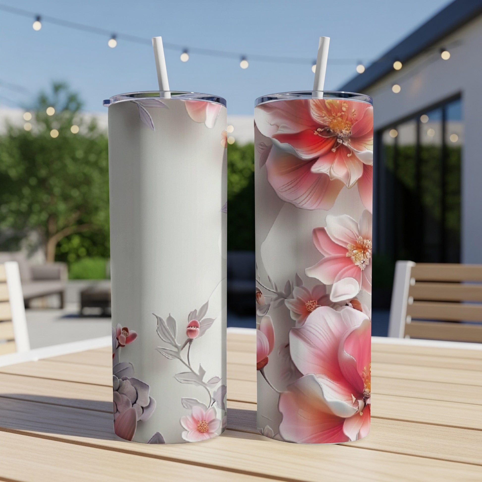 Two tumblers with floral designs on an outdoor table.