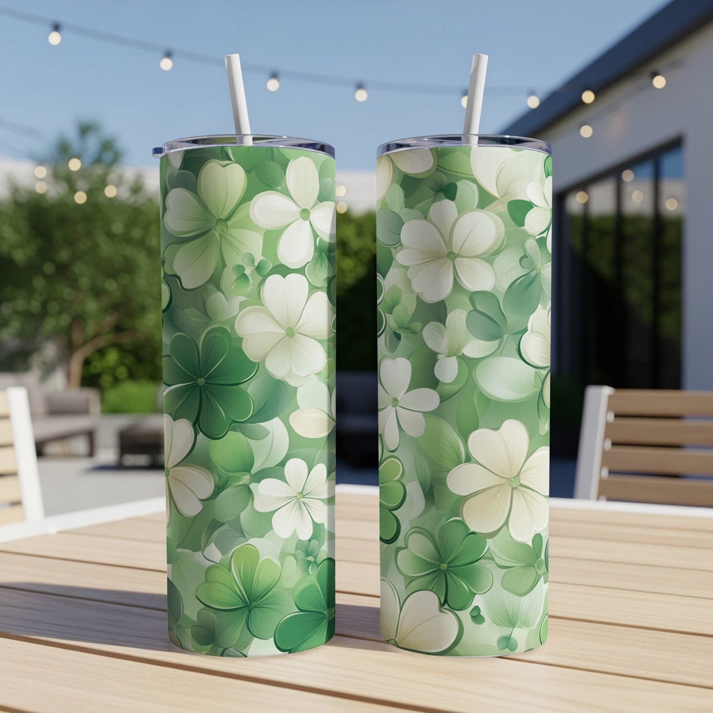 Two green tumblers with floral clover patterns and white straws.