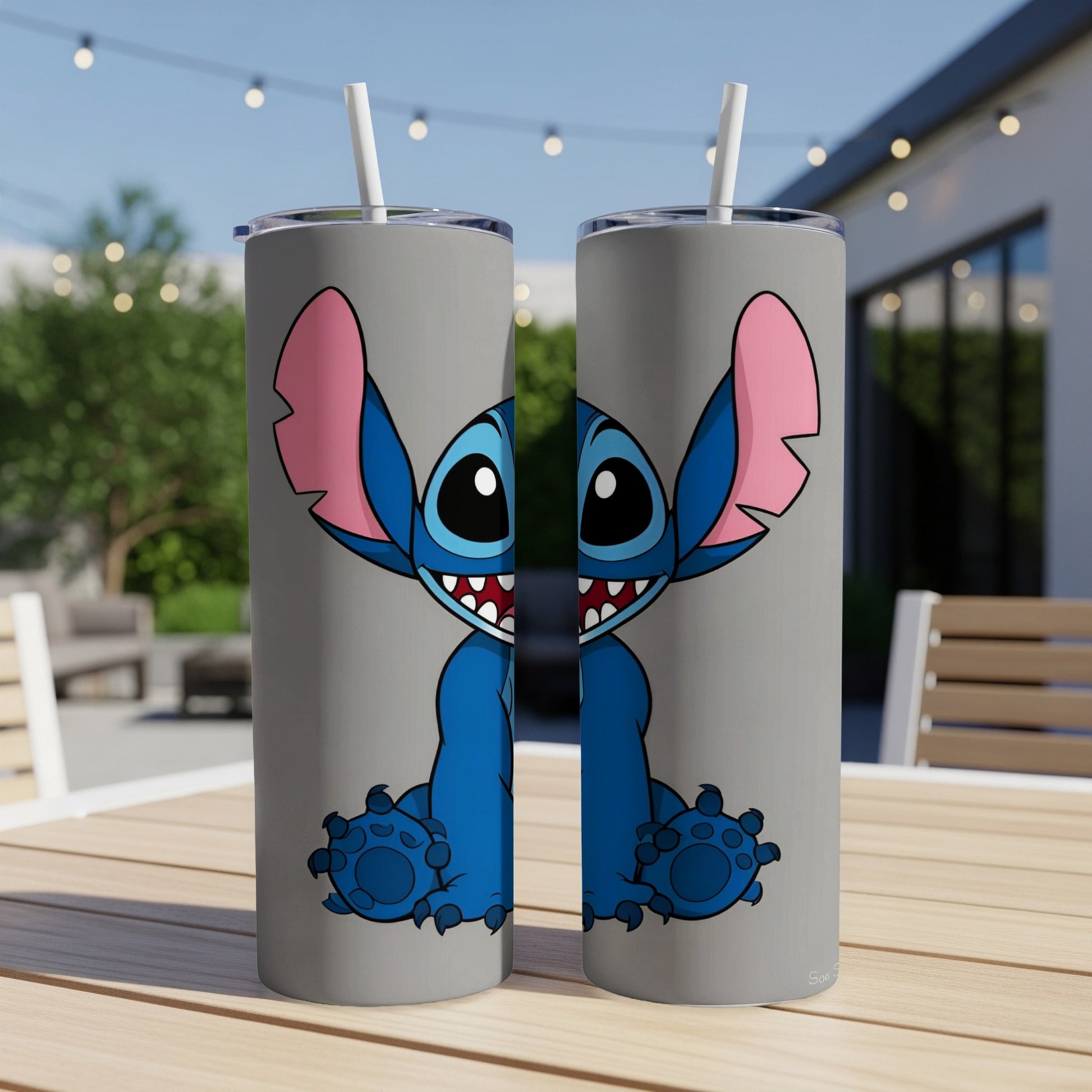 Two gray tumblers with a Stitch character design, resting on a wooden table.