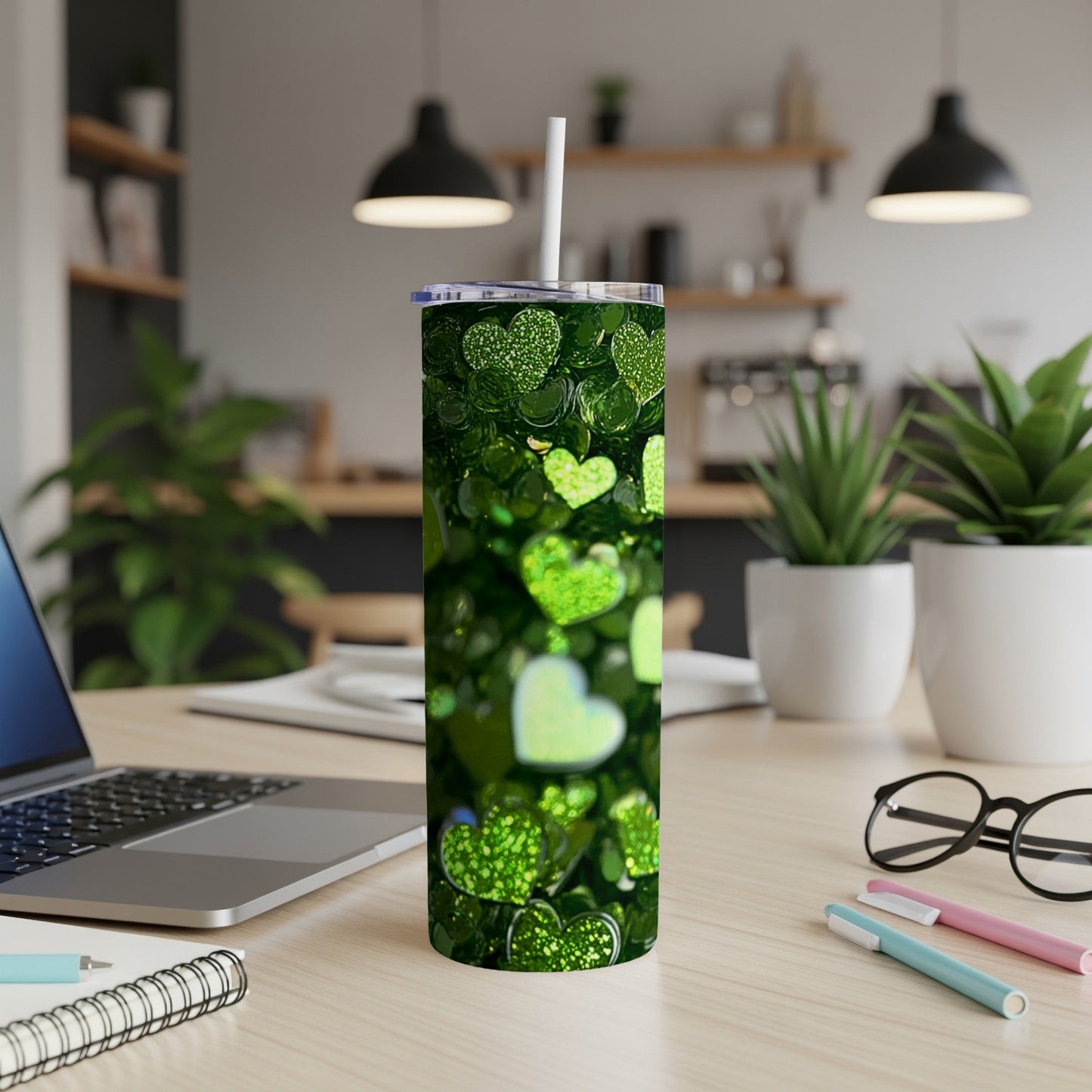 Green glitter heart tumbler with straw on a desk.