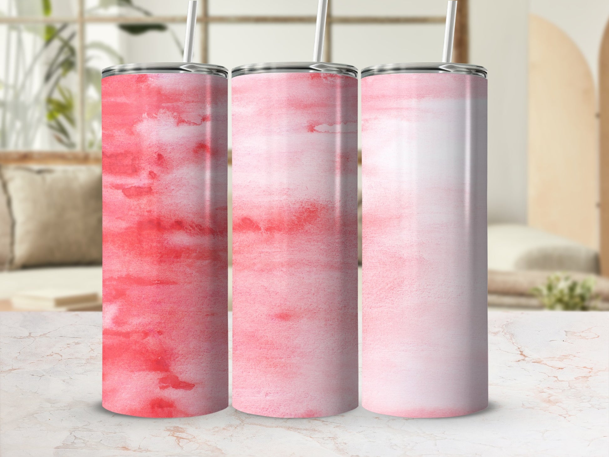 Three pink watercolor tumblers with straws, displayed on a marble surface.