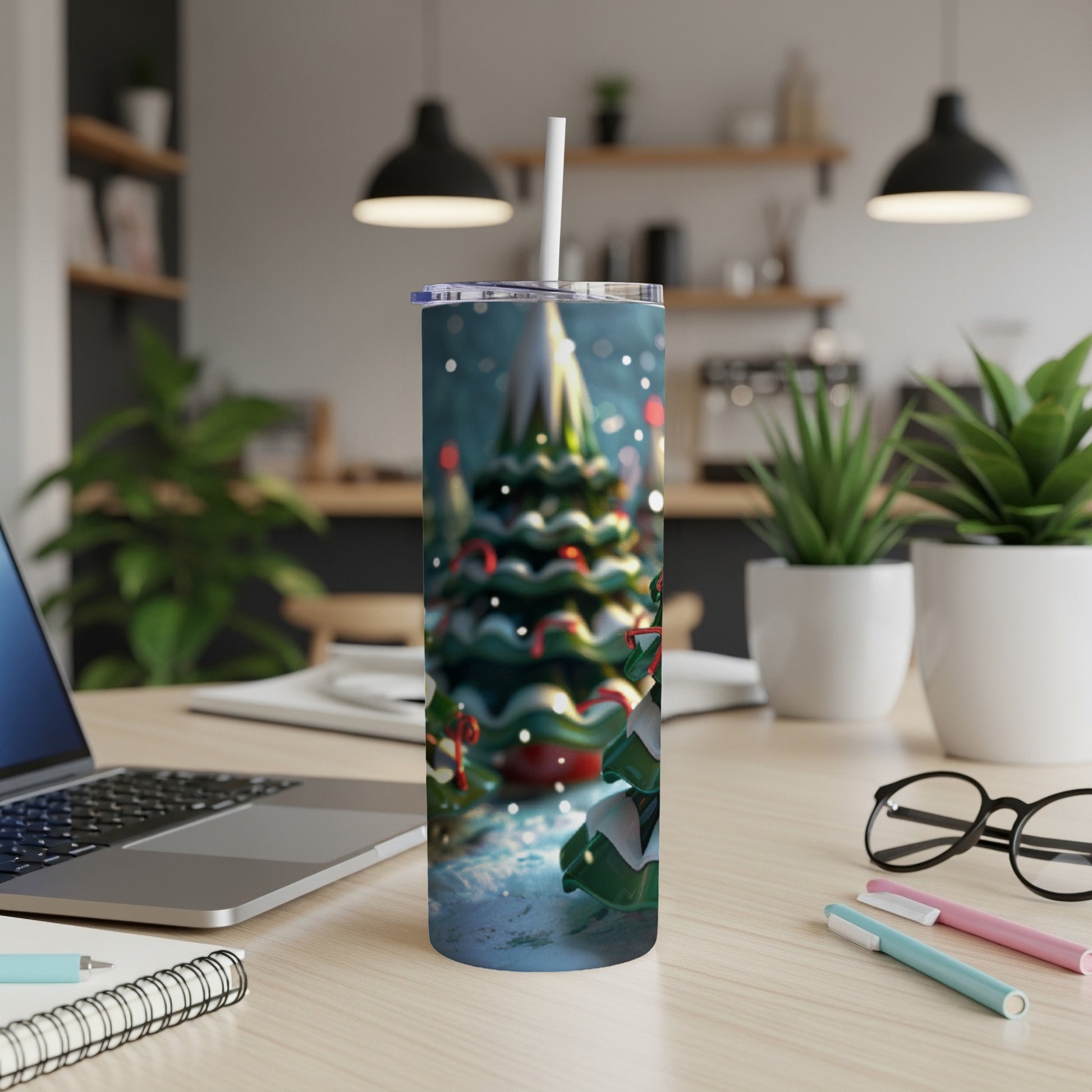 Christmas tree tumbler with straw, sitting on a desk next to a laptop.