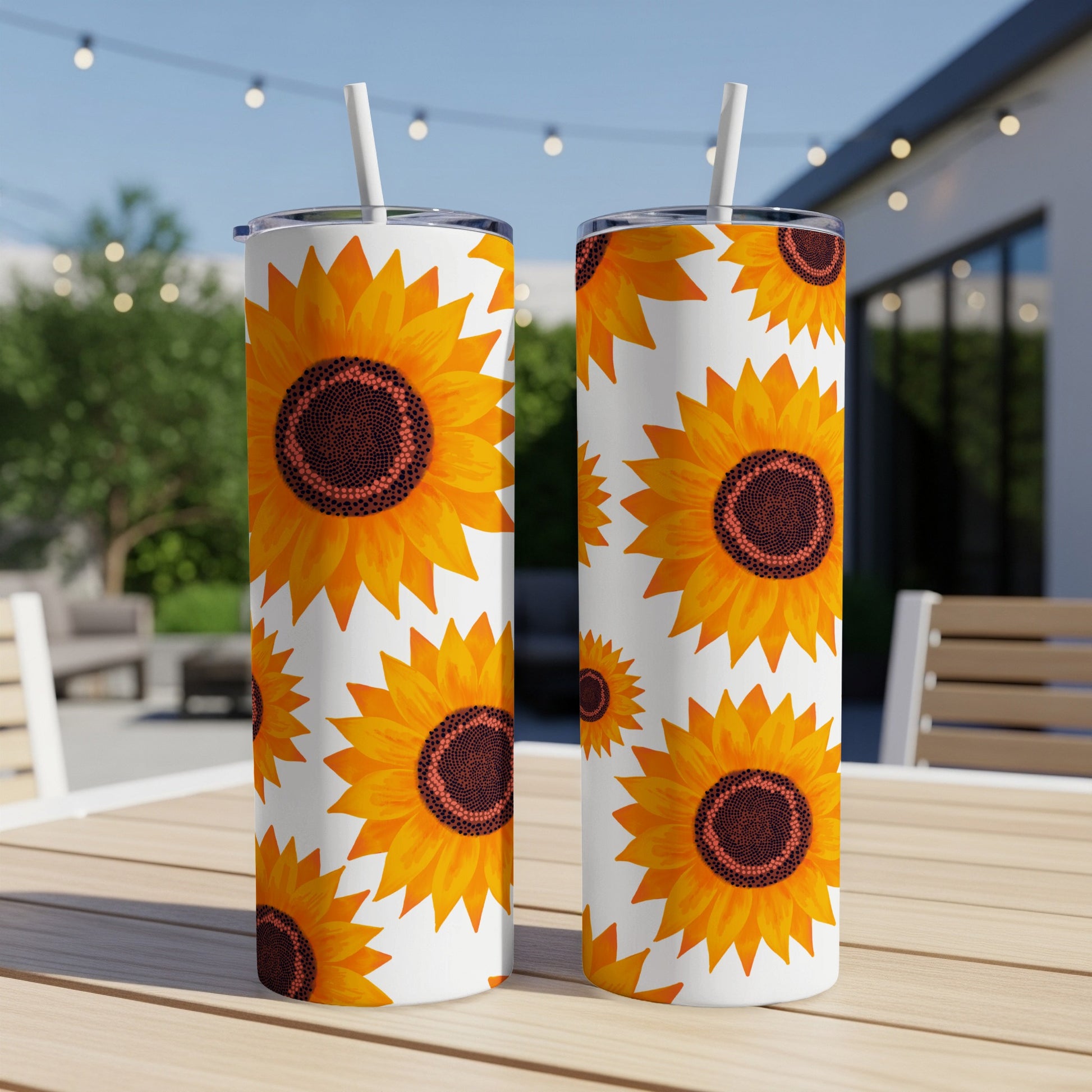 Two tall tumblers with a repeating sunflower pattern on a wooden table.