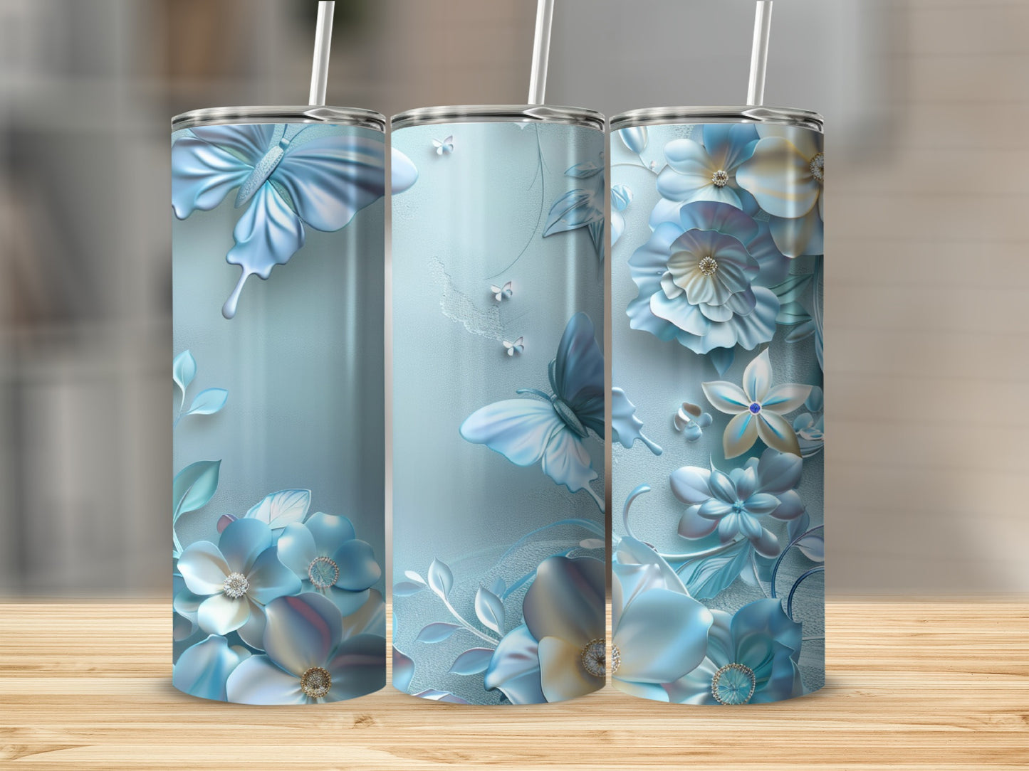 Three blue tumblers with butterflies and floral designs sit on a wooden surface.