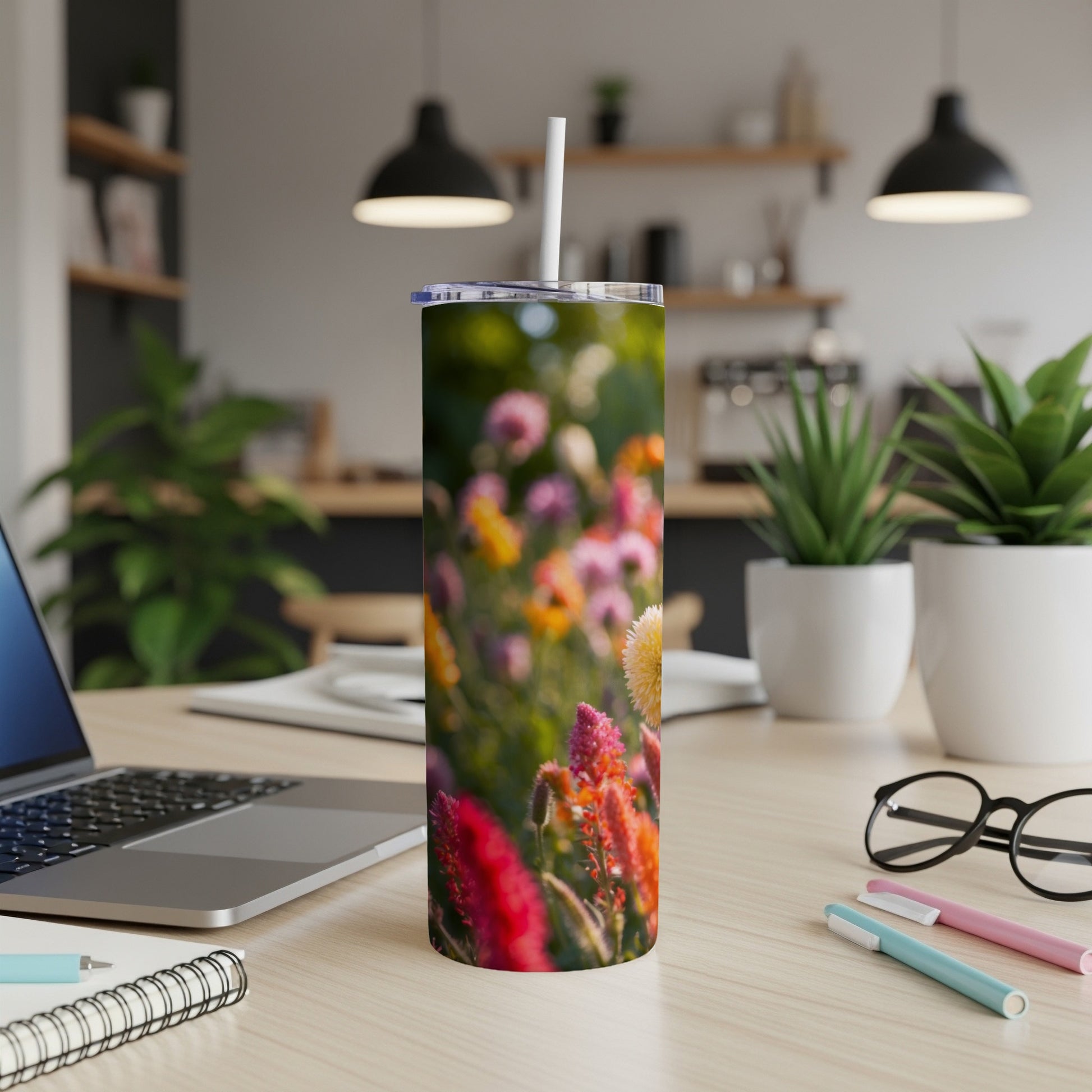 Floral pattern tumbler with straw on a desk beside a laptop.