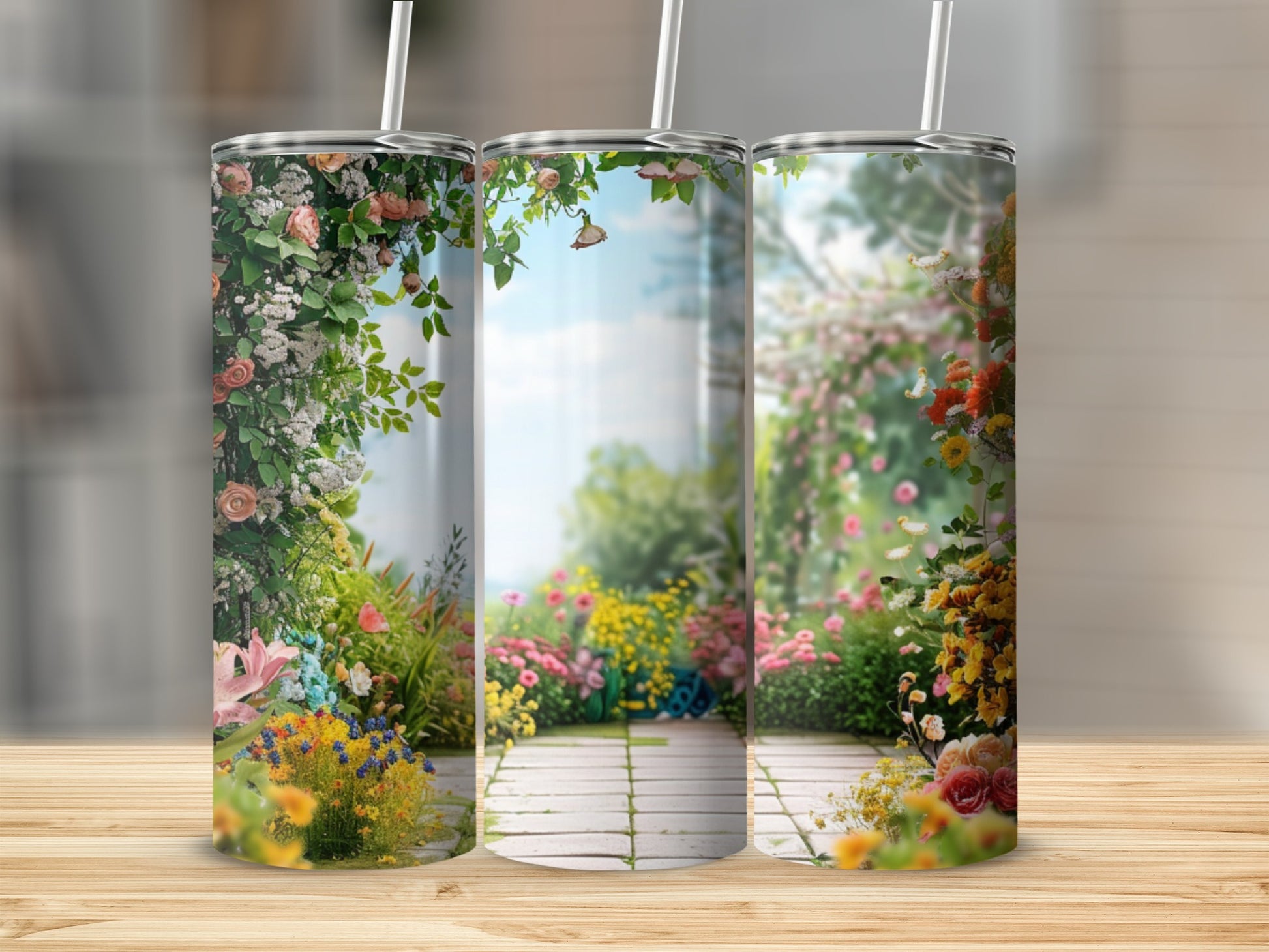 Three tumblers adorned with a floral garden path and blue sky design.