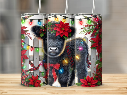 Fluffy black cow wearing festive garland and poinsettias.