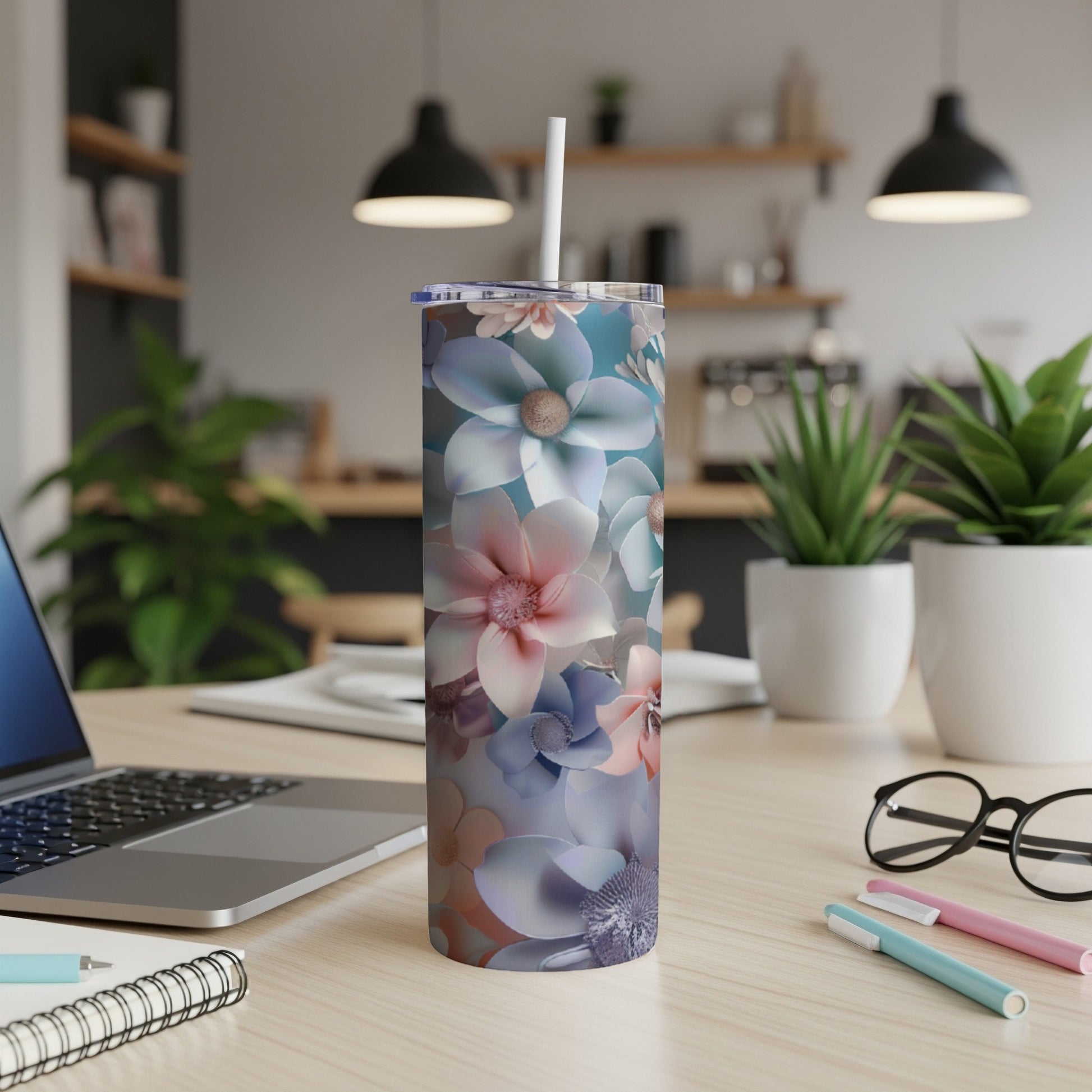 Floral patterned skinny tumbler with straw on a desk.