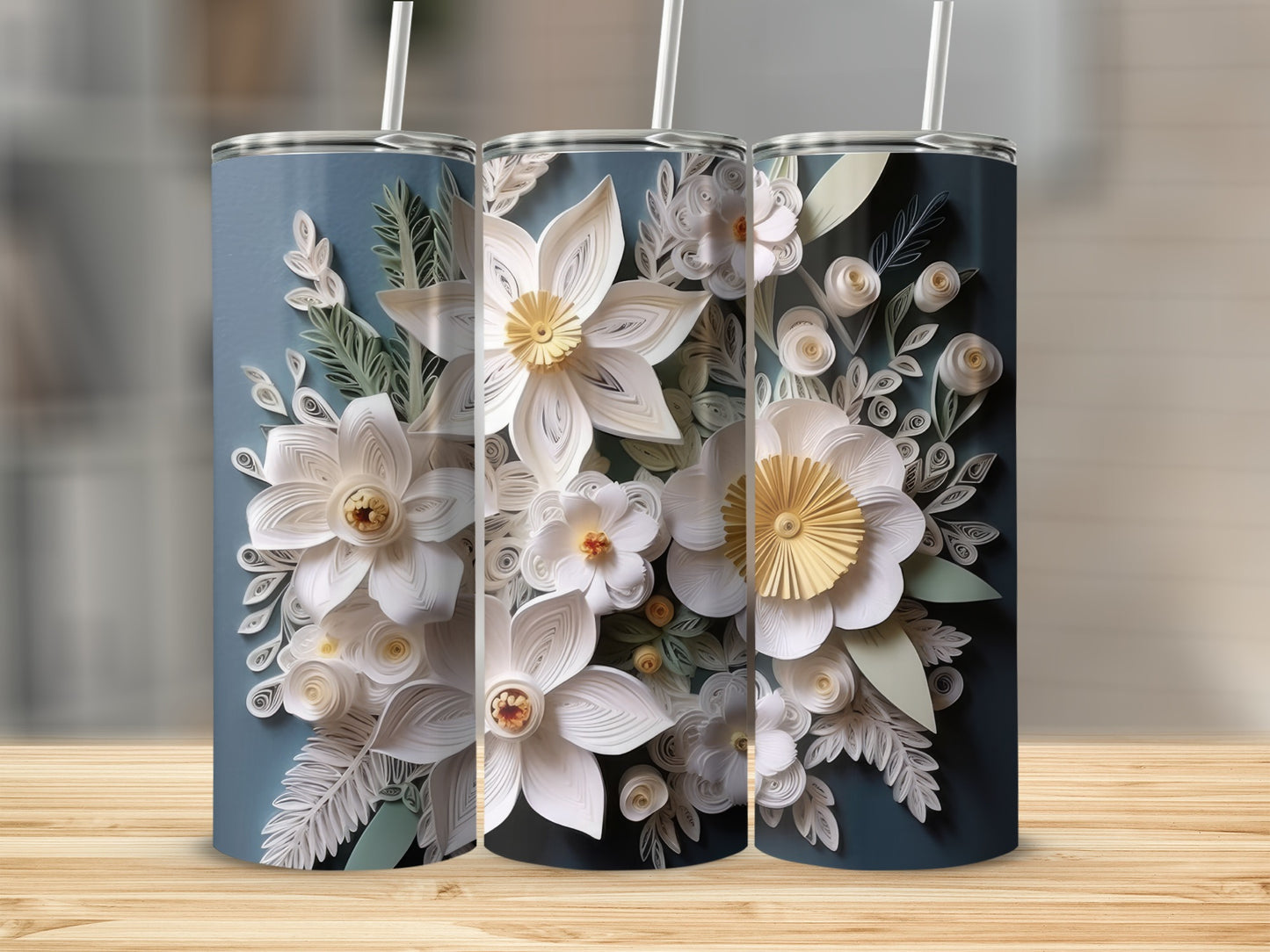 Three tall tumblers with white paper floral designs on a blue background.