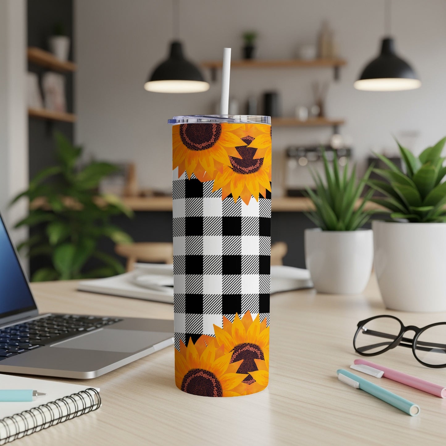 Sunflower and buffalo plaid tumbler with straw on a desk.
