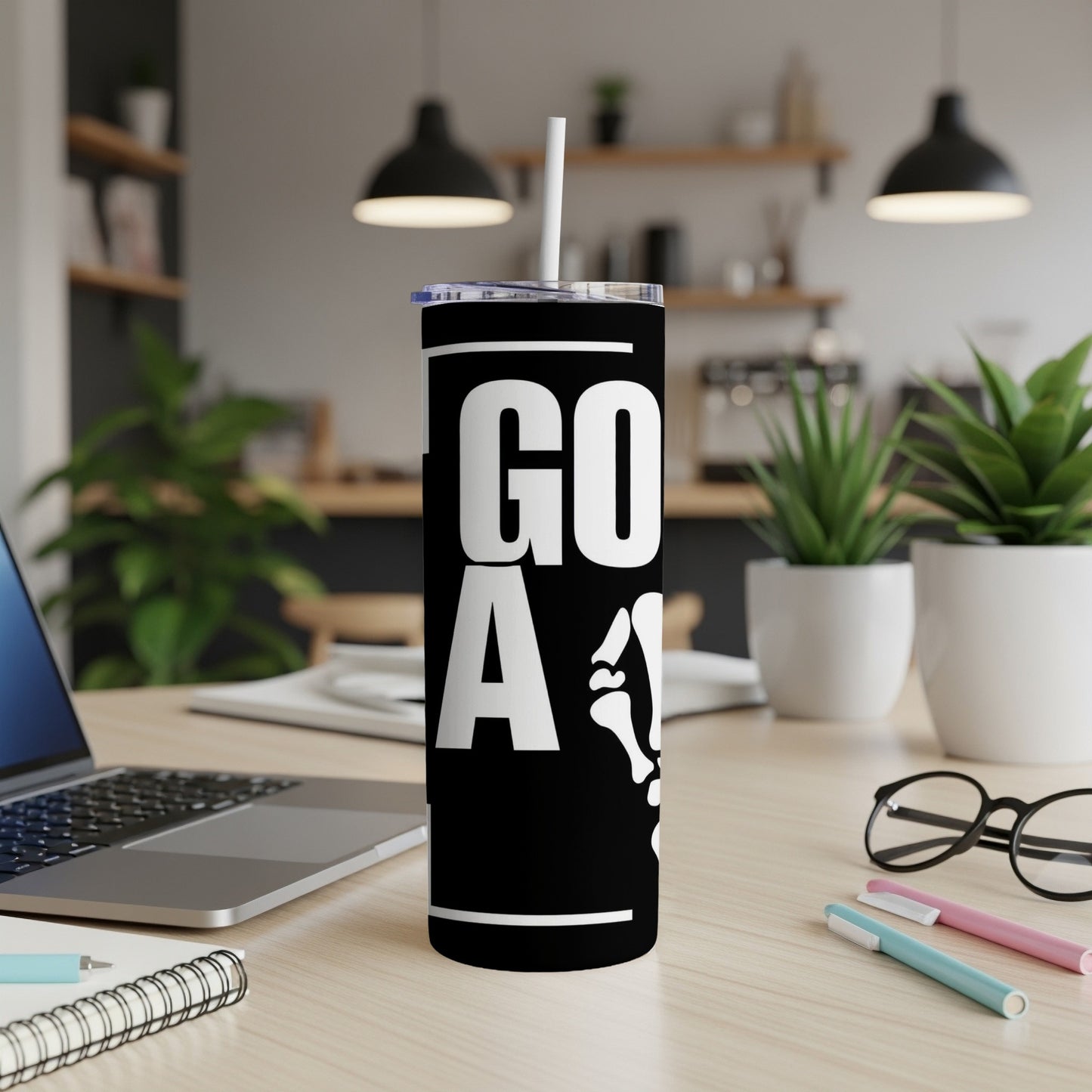 Black tumbler with "GO A" and skeleton bone graphics, on a desk.