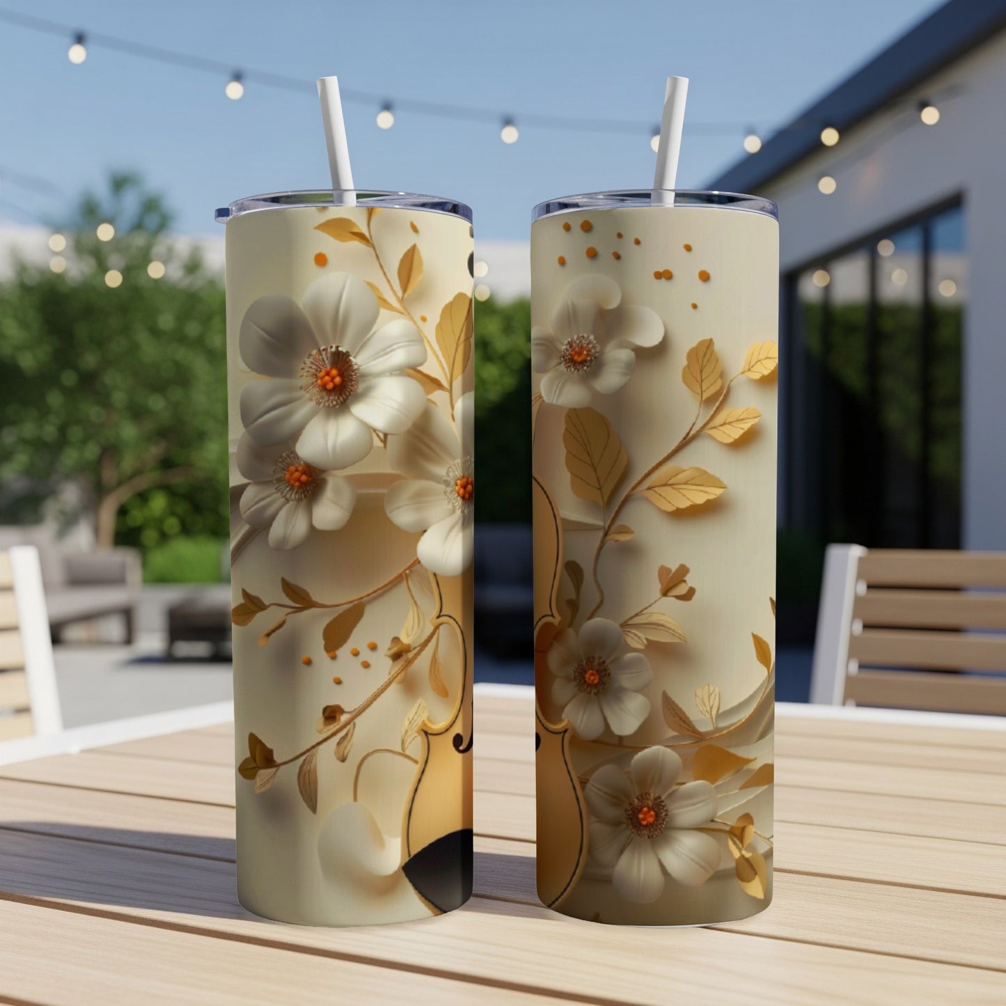 Two tumblers with floral and vine designs sit on a table outdoors.