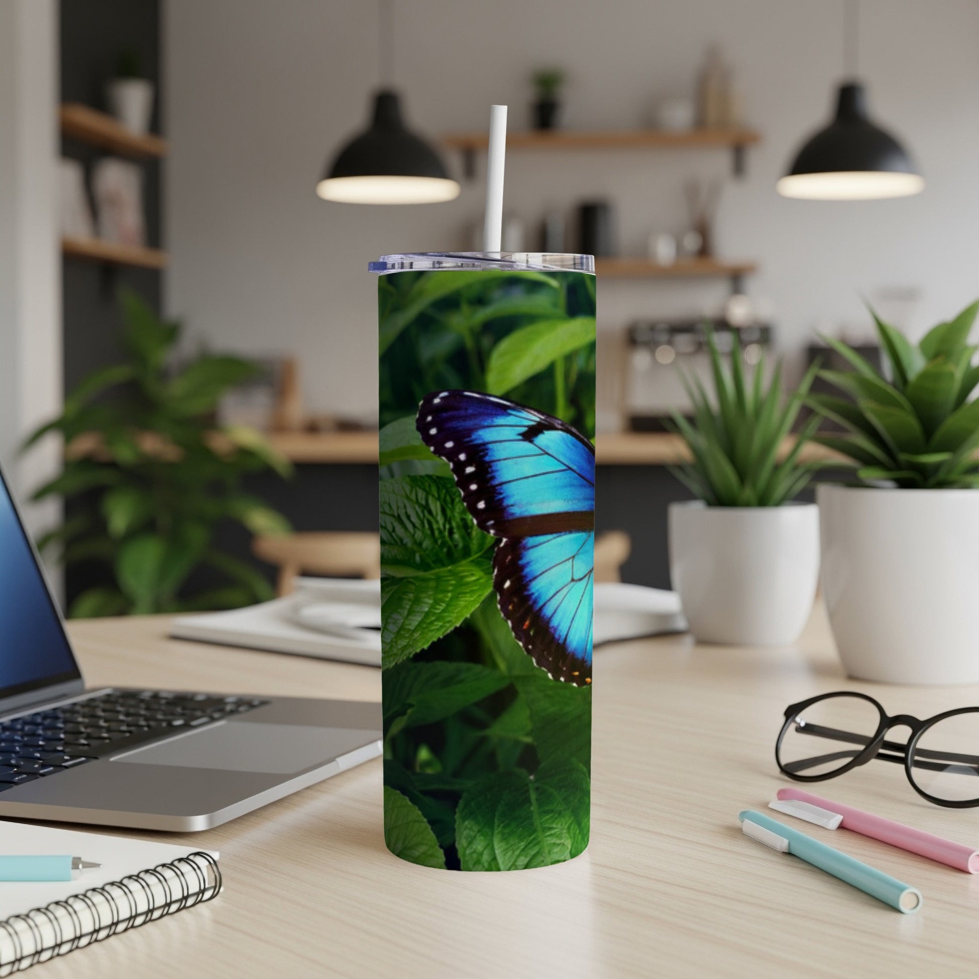 Blue butterfly on a green leaf pattern tumbler with a white straw.