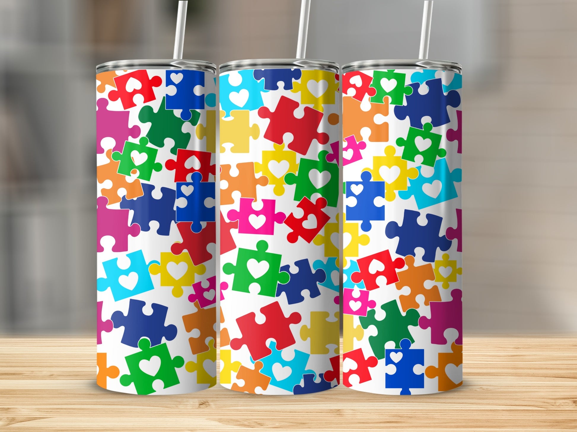 Three tumblers with colorful puzzle piece patterns and hearts.