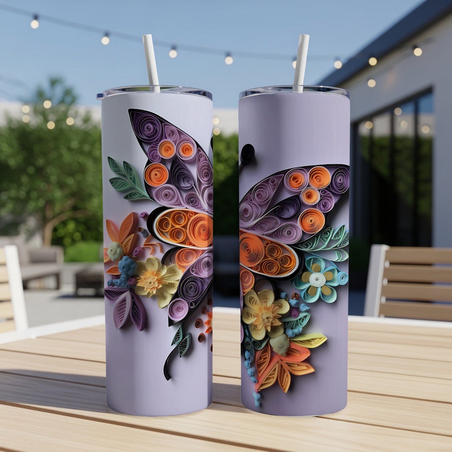 Two skinny tumblers with quilled dragonfly and floral designs on a table.
