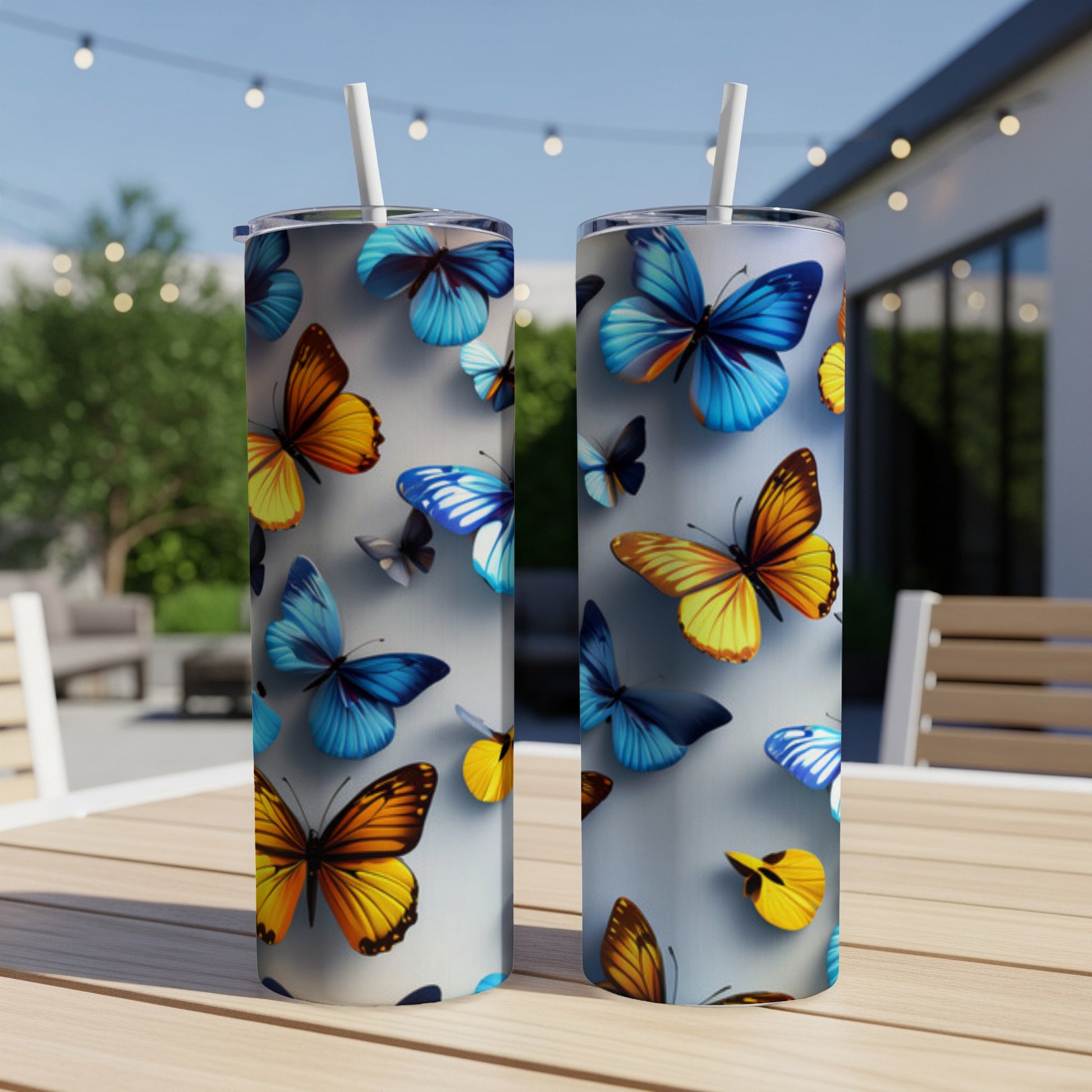Two tumblers with colorful butterflies and straw on a table.