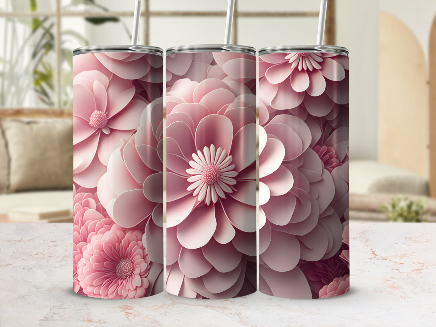 Three pink floral tumblers with straws on a marble surface.