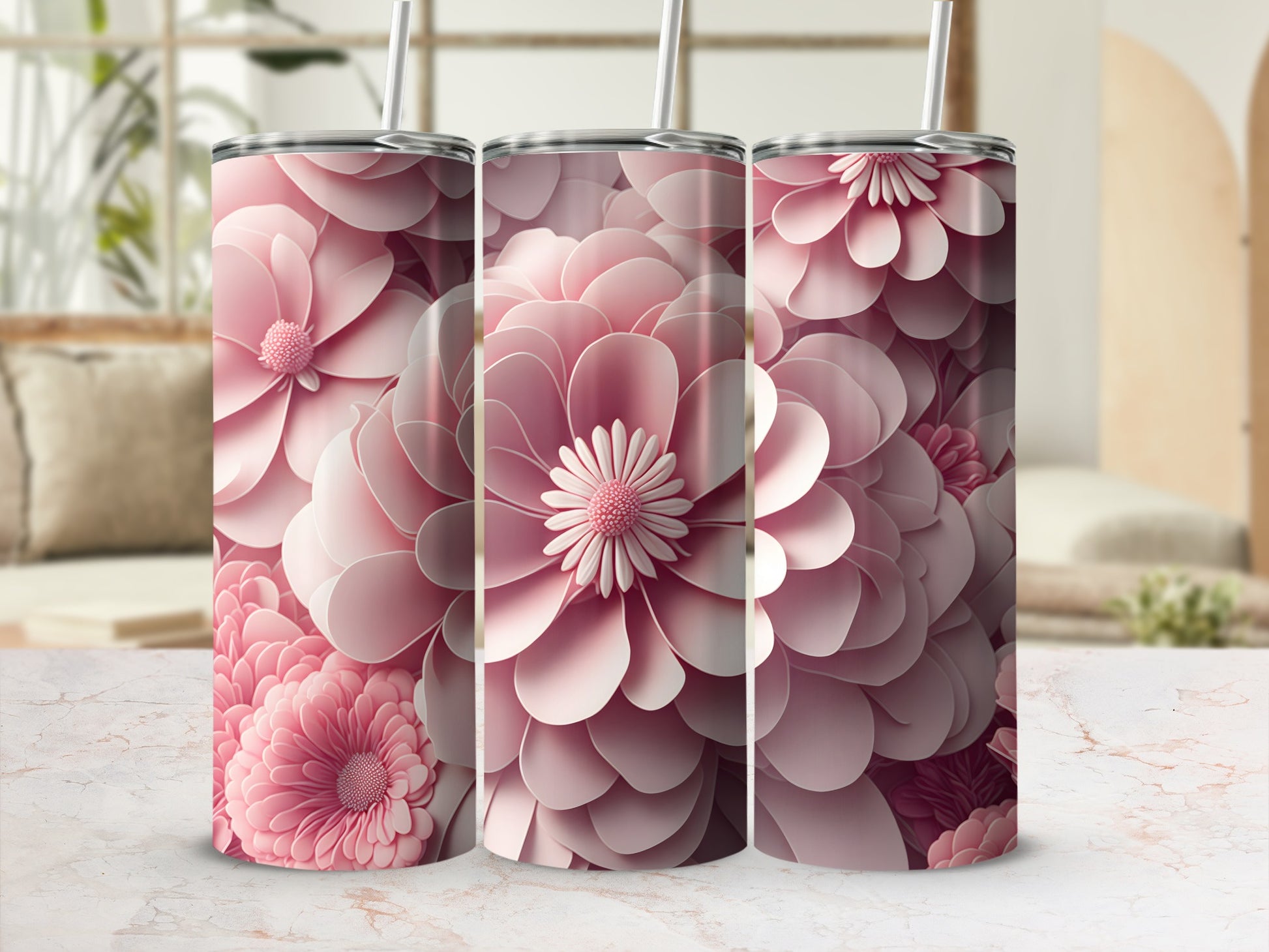 Three pink floral tumblers with straws on a marble surface.