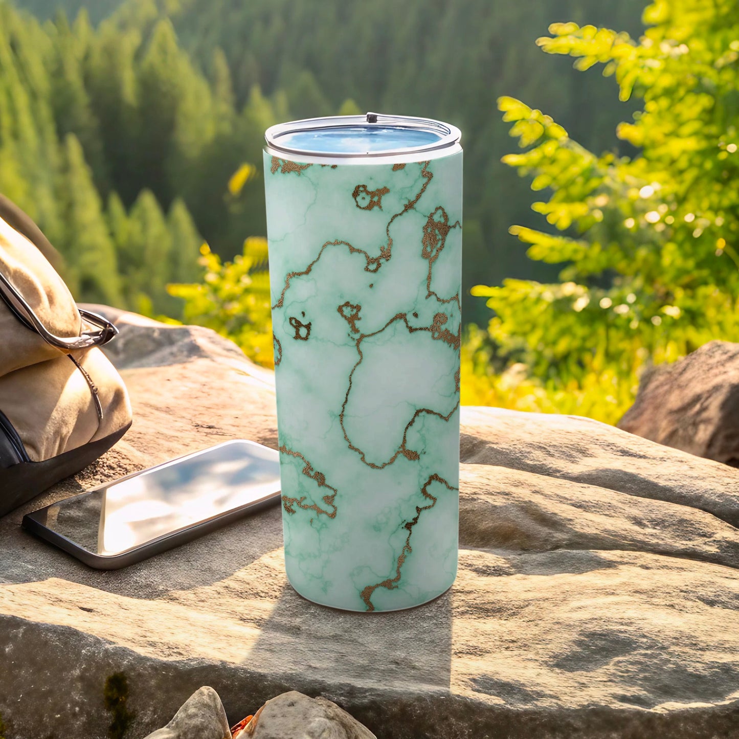 Mint green marbled tumbler with gold accents on a rock.