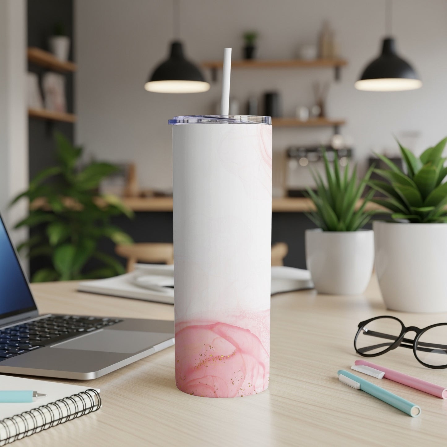 White tumbler with pink watercolor design and straw on a desk.