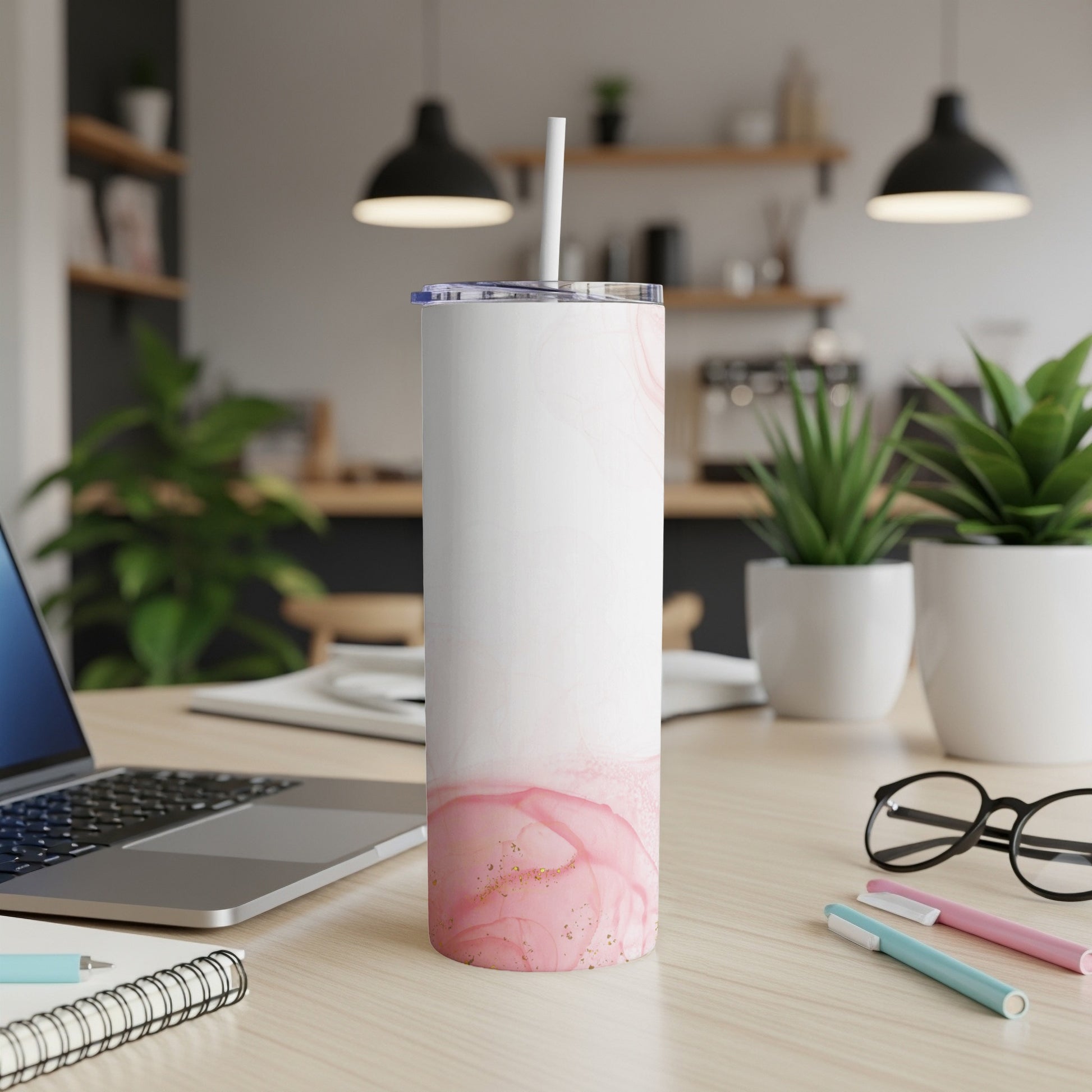 White tumbler with pink watercolor design and straw on a desk.