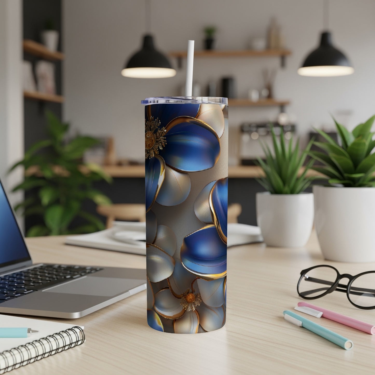 Blue and gold floral tumbler with straw on desk.