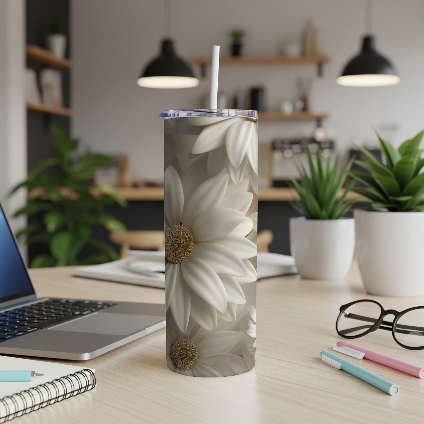 White daisy flowers on a slim tumbler with a straw.