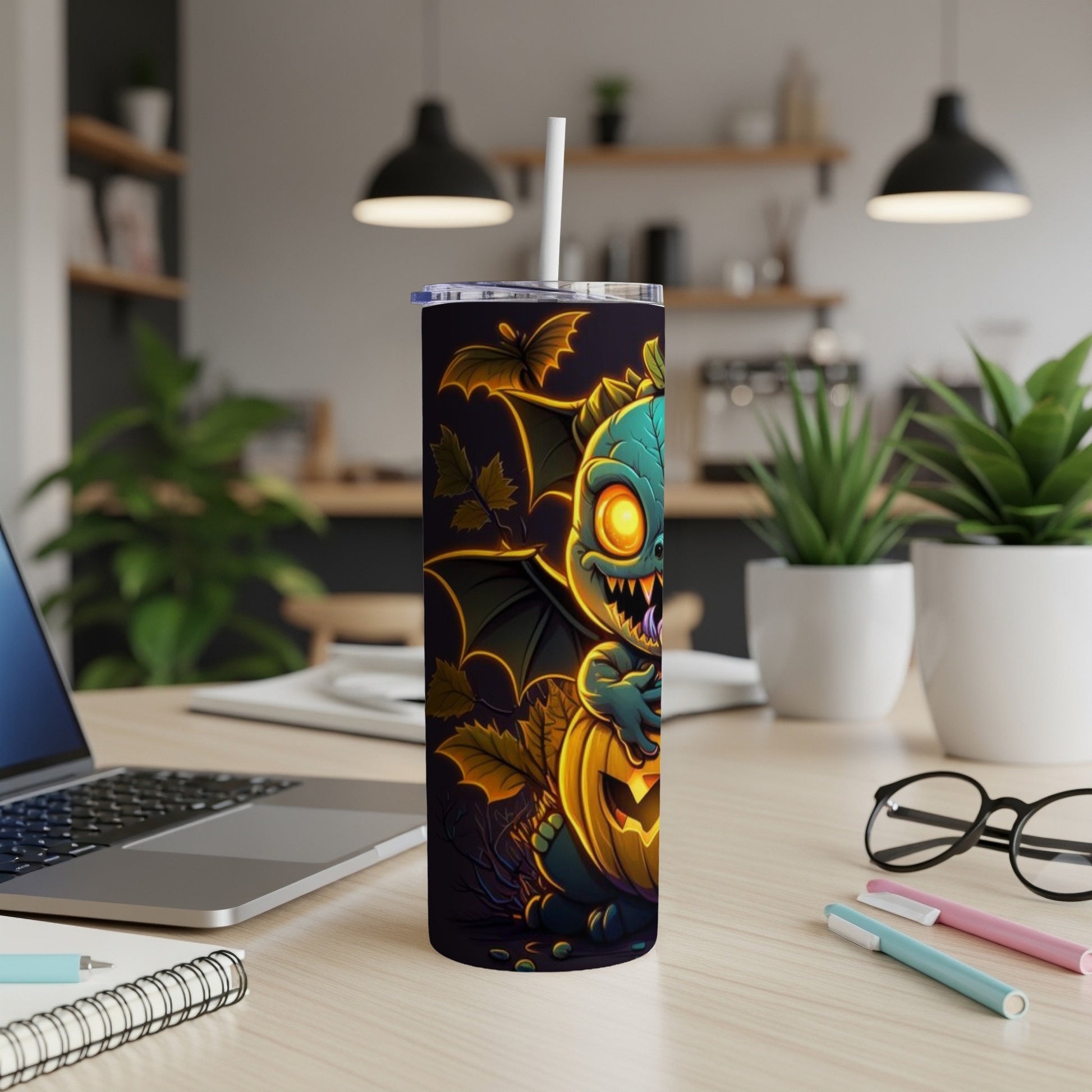 Tumbler with cartoon monster and pumpkin Halloween design, on desk.