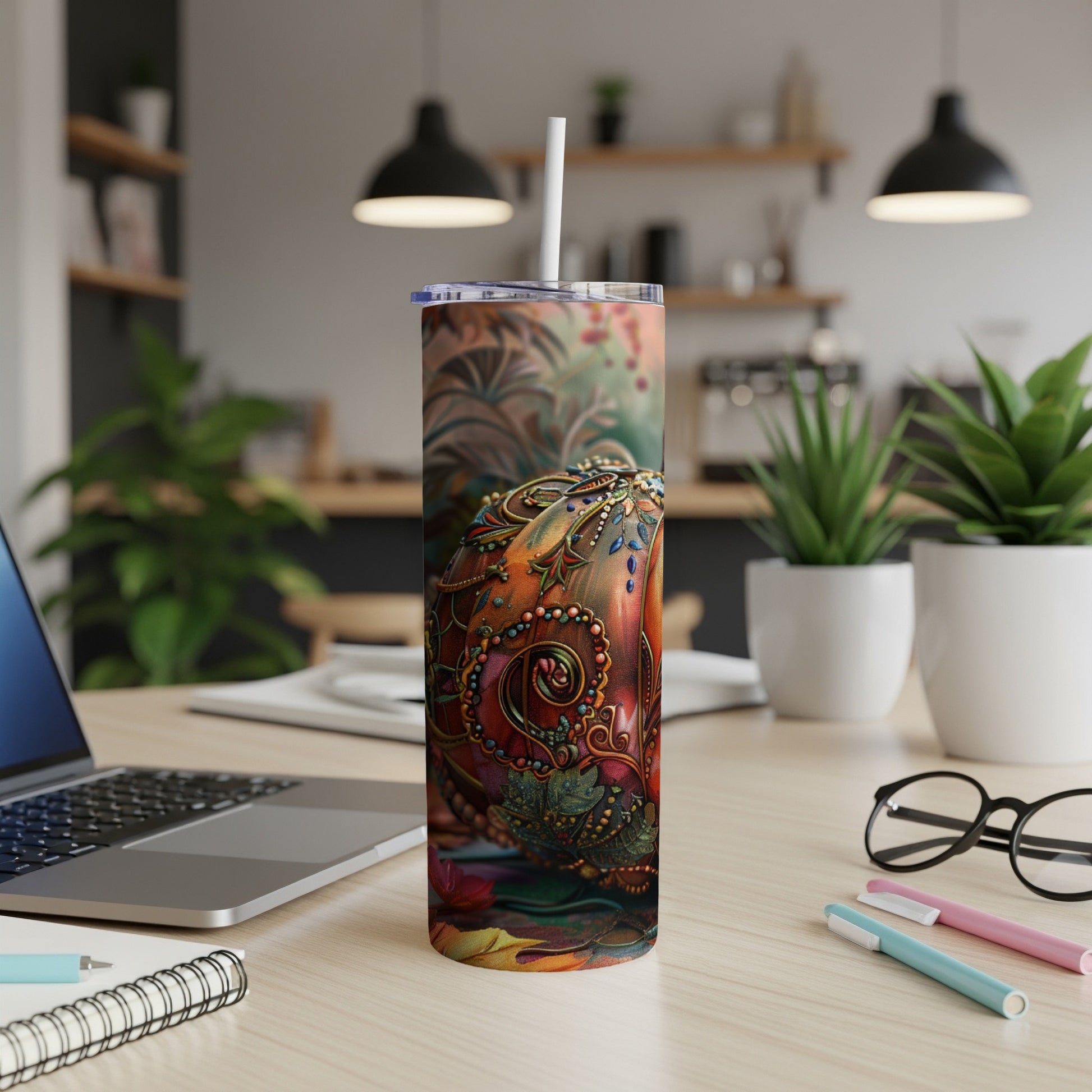 Tumbler with a colorful, ornate pumpkin design rests on a desk.
