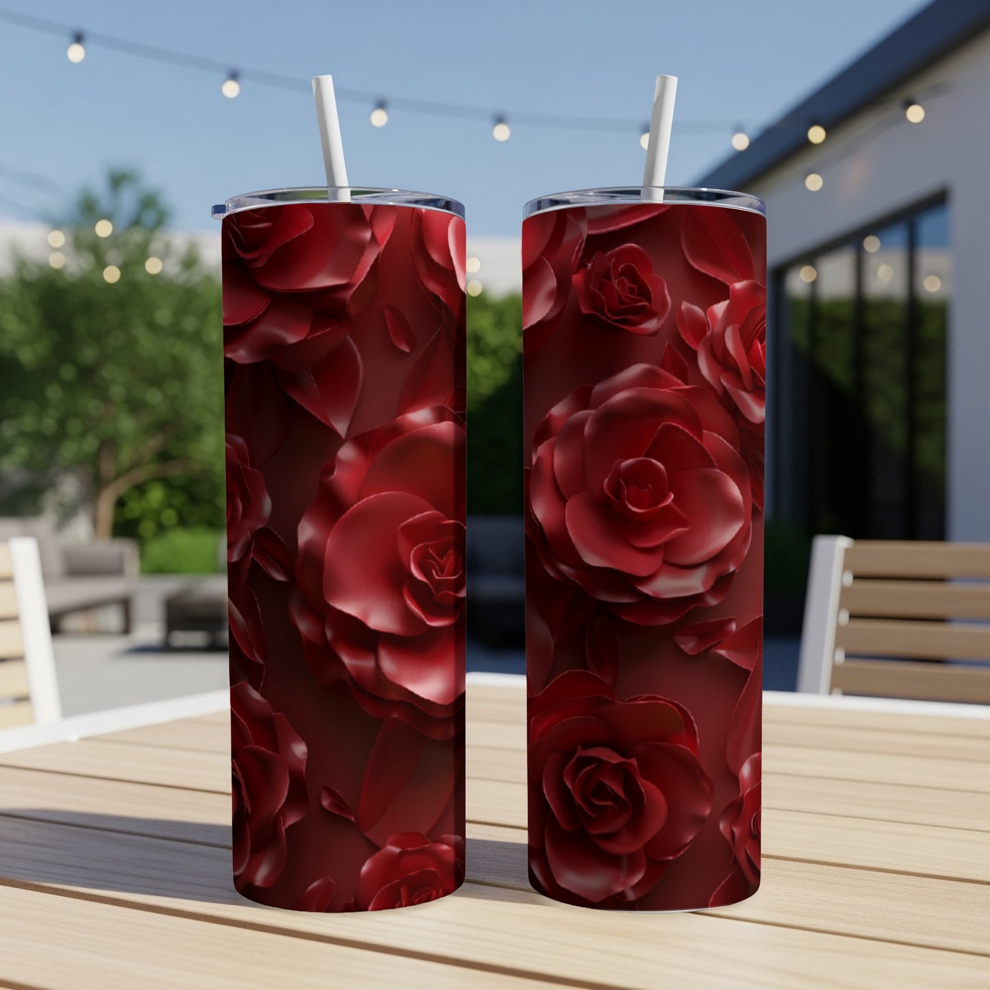 Two dark red rose pattern tumblers with straws on a wooden table.