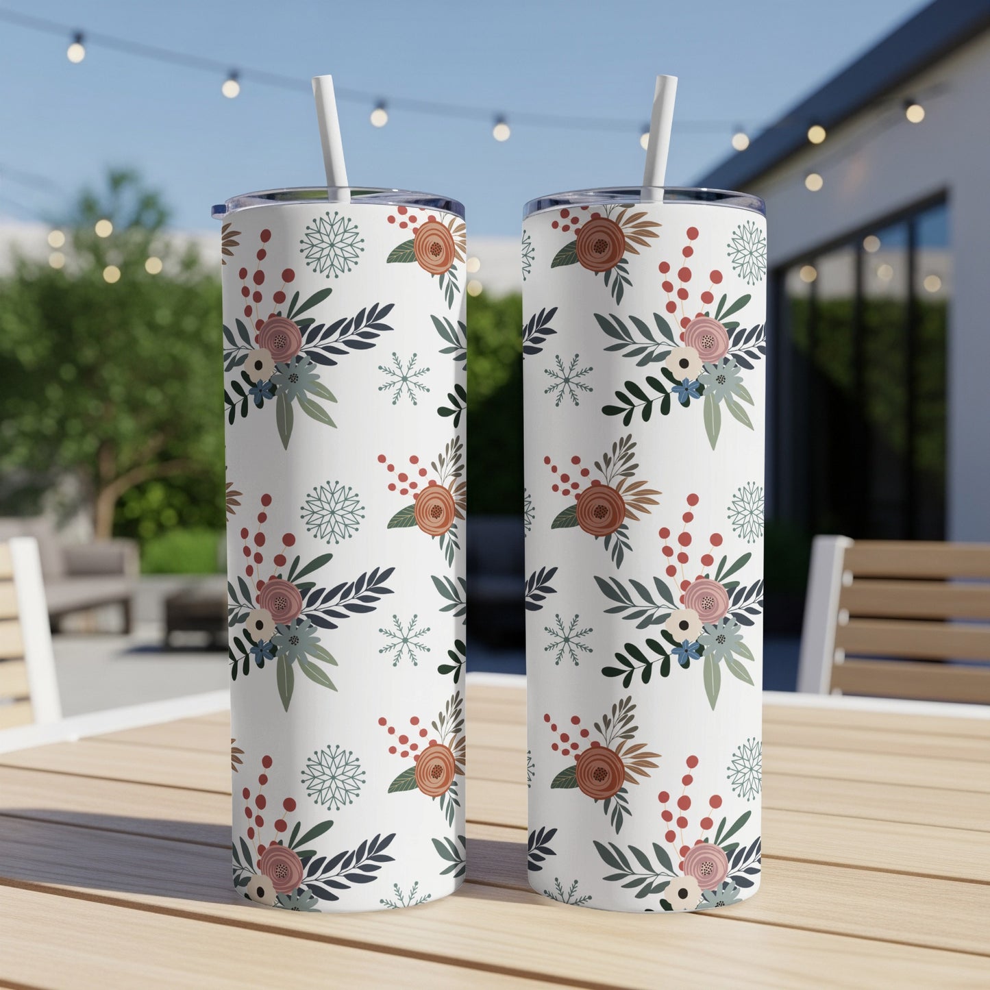 Two white tumblers with floral and snowflake pattern on a table.