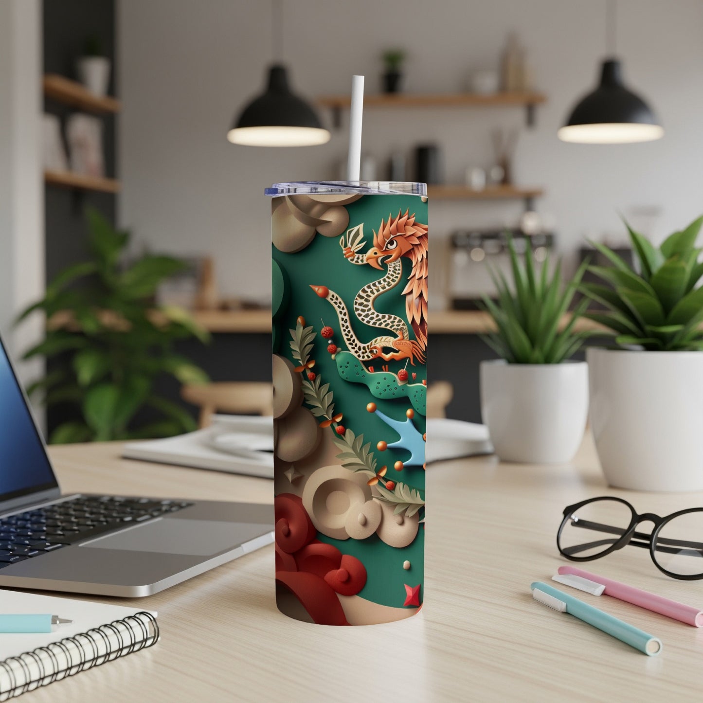Green tumbler with dragon and floral design, on a desk.
