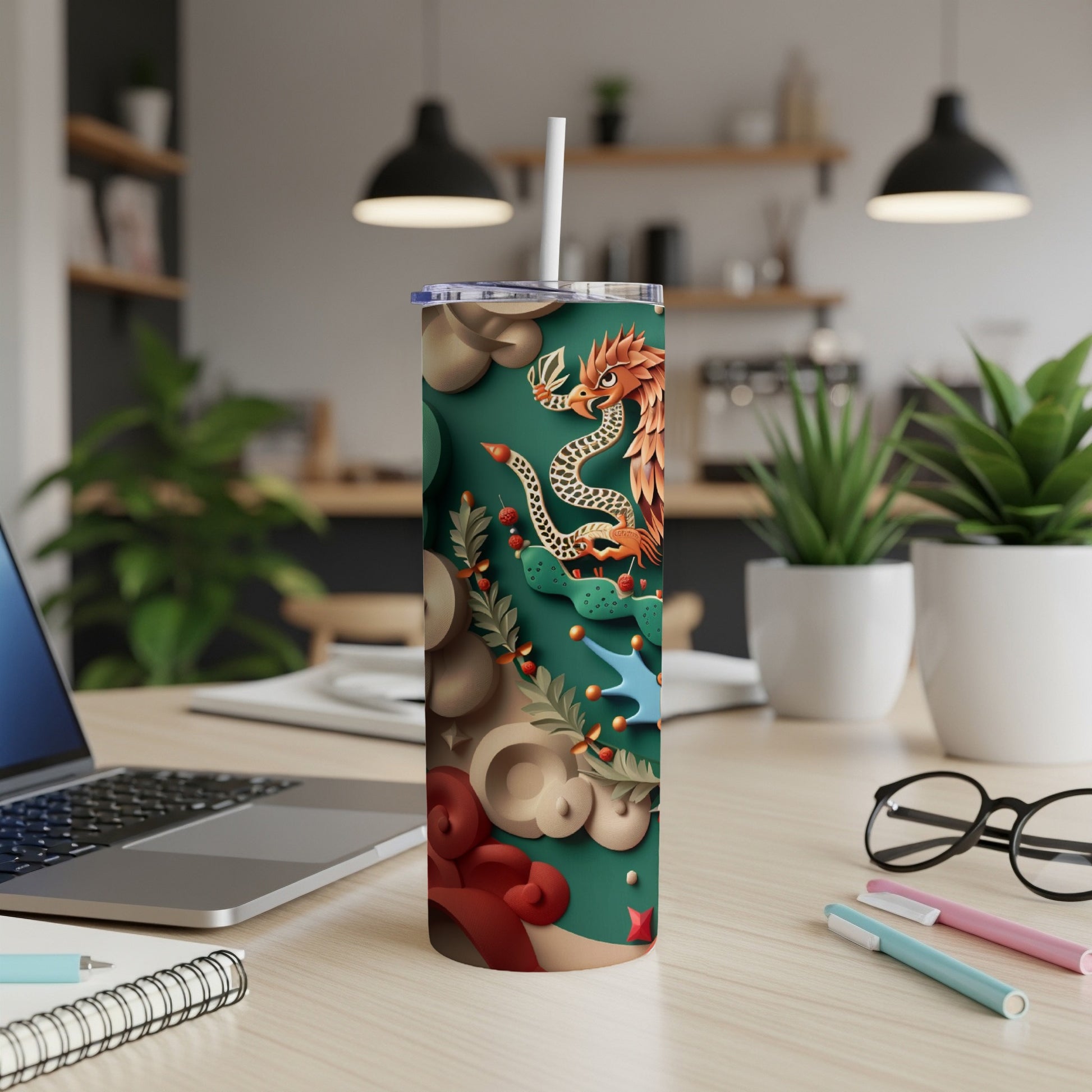 Green tumbler with dragon and floral design, on a desk.