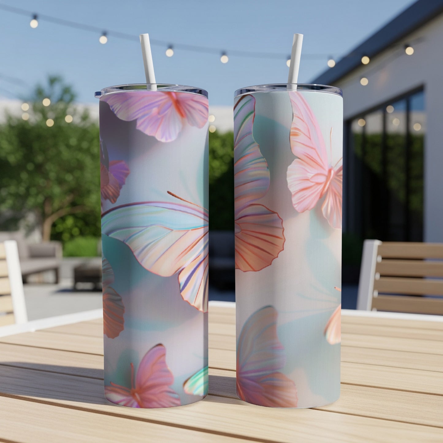 Two tumblers with a pastel butterfly pattern sit on a wooden table outdoors.