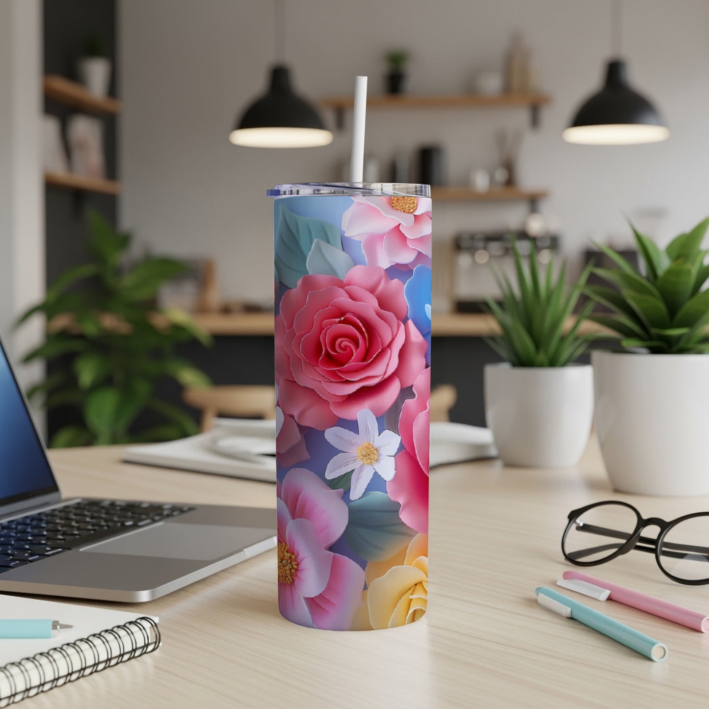 Floral tumbler with straw on a desk next to a laptop.