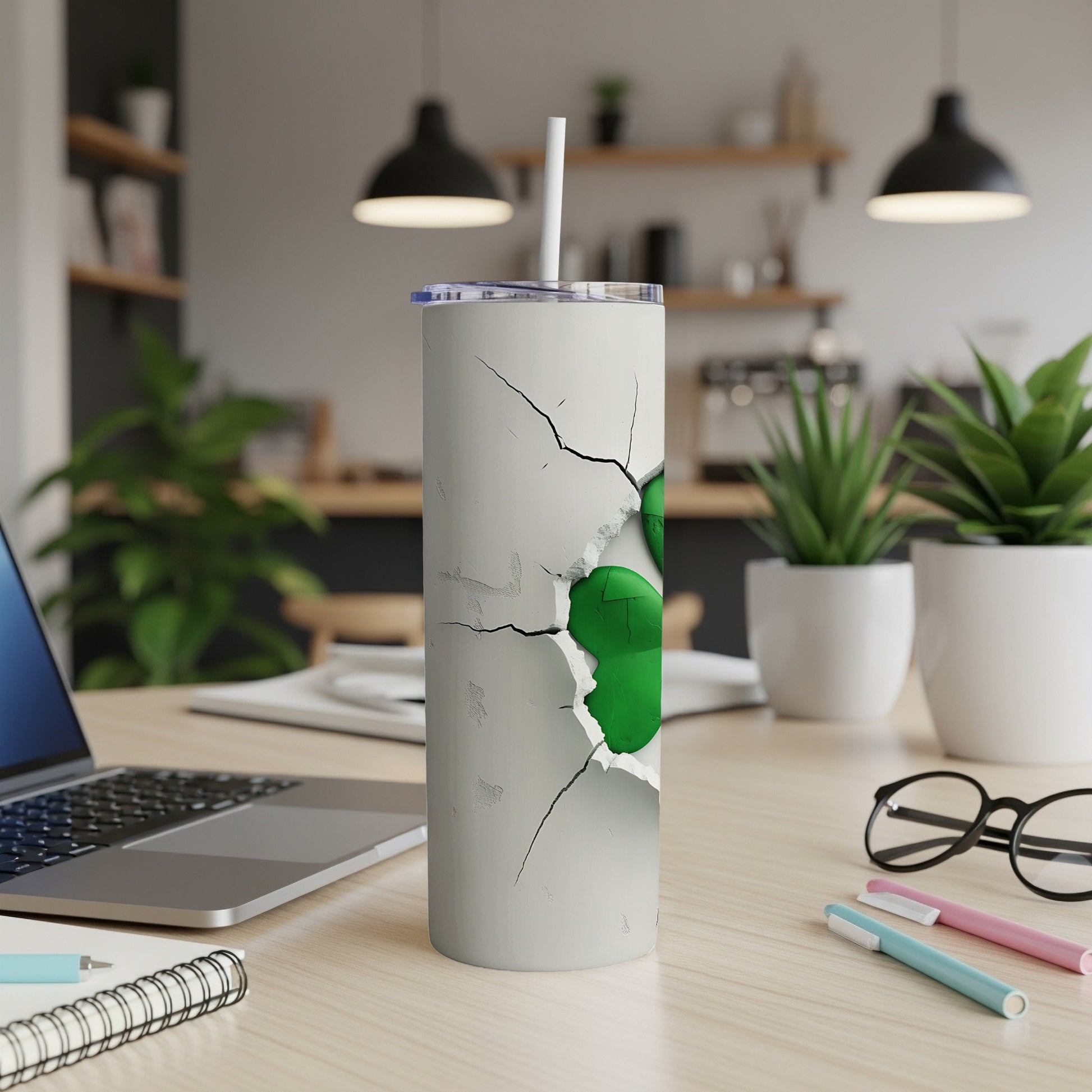 White tumbler with cracked design revealing green inside, straw inserted.