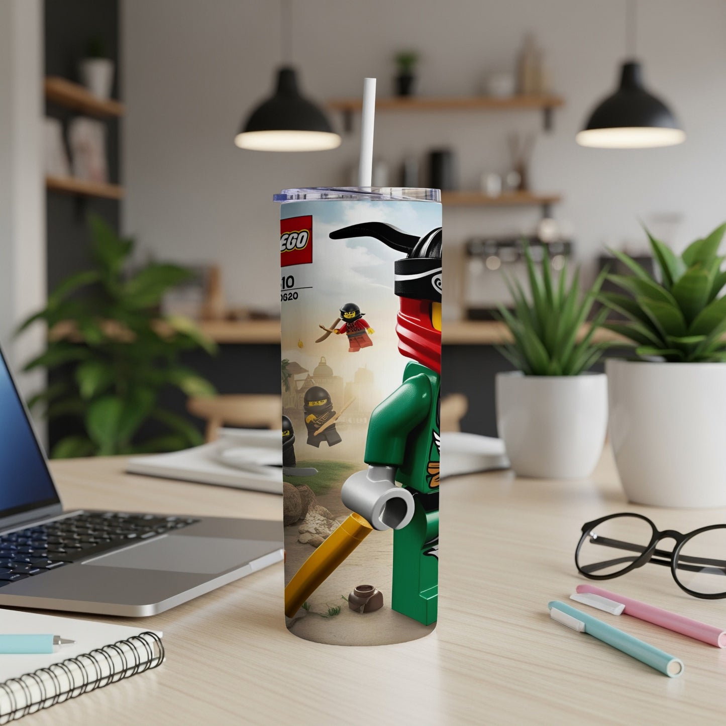 Lego Ninjago tumbler with characters and a straw on a desk.