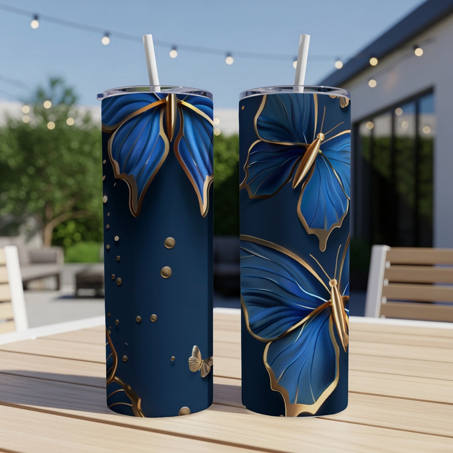 Two blue tumblers with gold butterflies and dots, displayed outdoors.